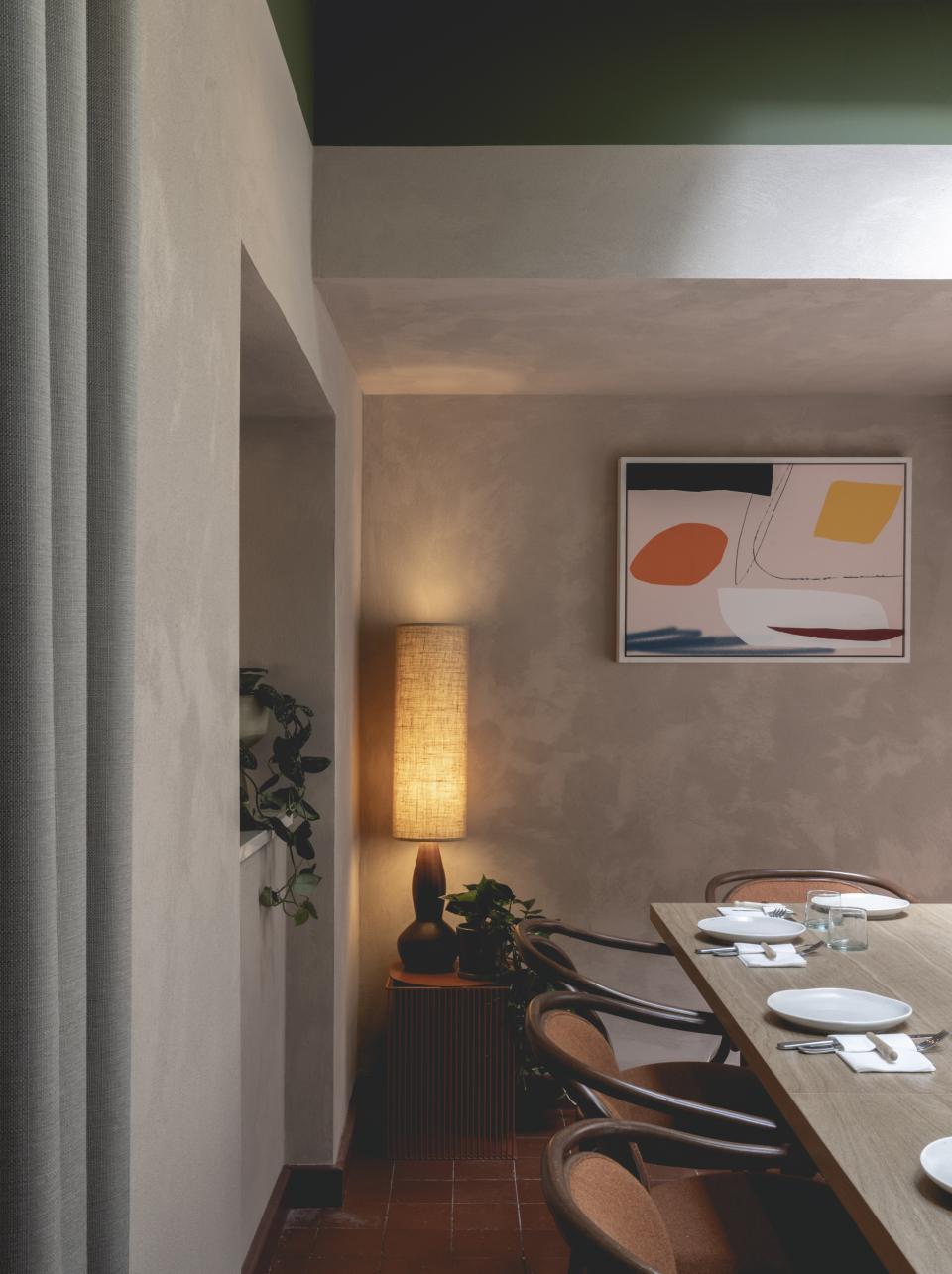 Welcoming interior of Honey & Co Bloomsbury featuring a wooden table, modern lighting, and contemporary artwork on the walls.