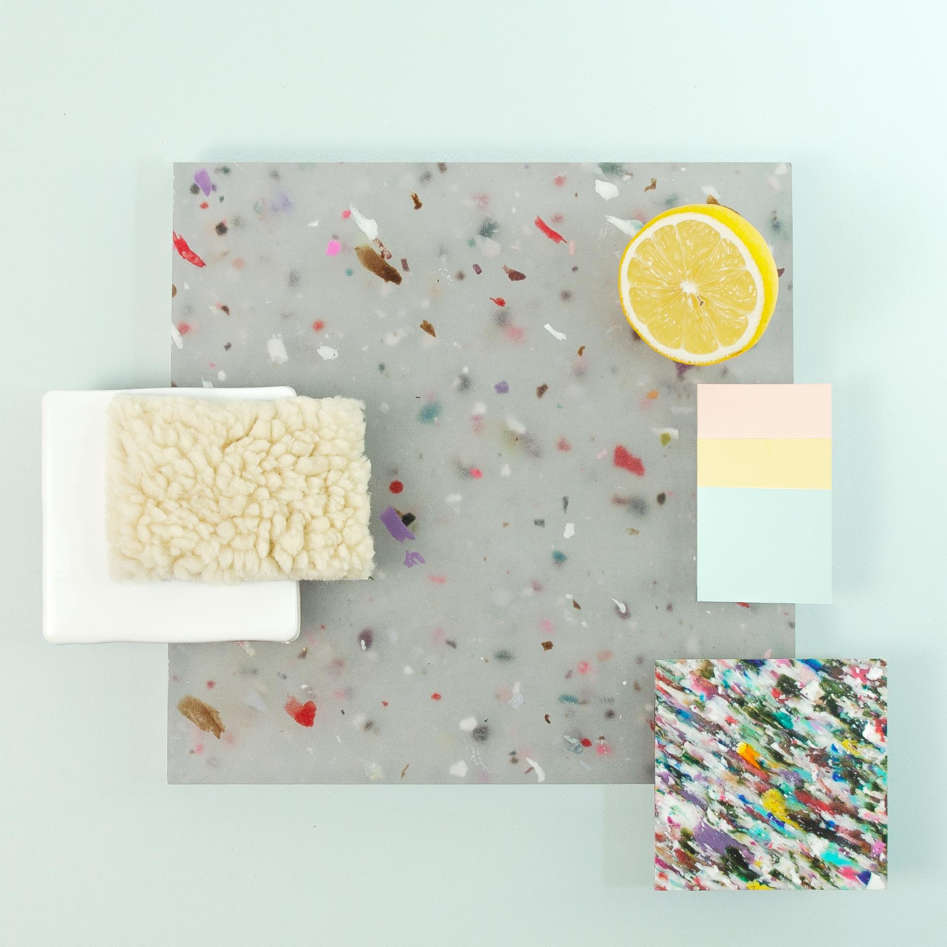 Colorful recycled material samples and a lemon slice displayed on a light blue surface, highlighting Smile Plastics' innovative designs.