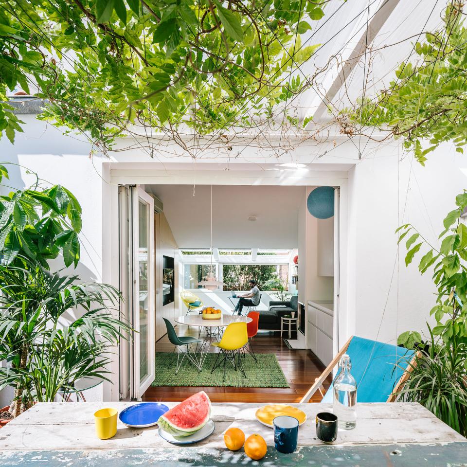 Converted attic with oversized bathtub, concealed entrance, and a vibrant, sunlit dining area filled with greenery.