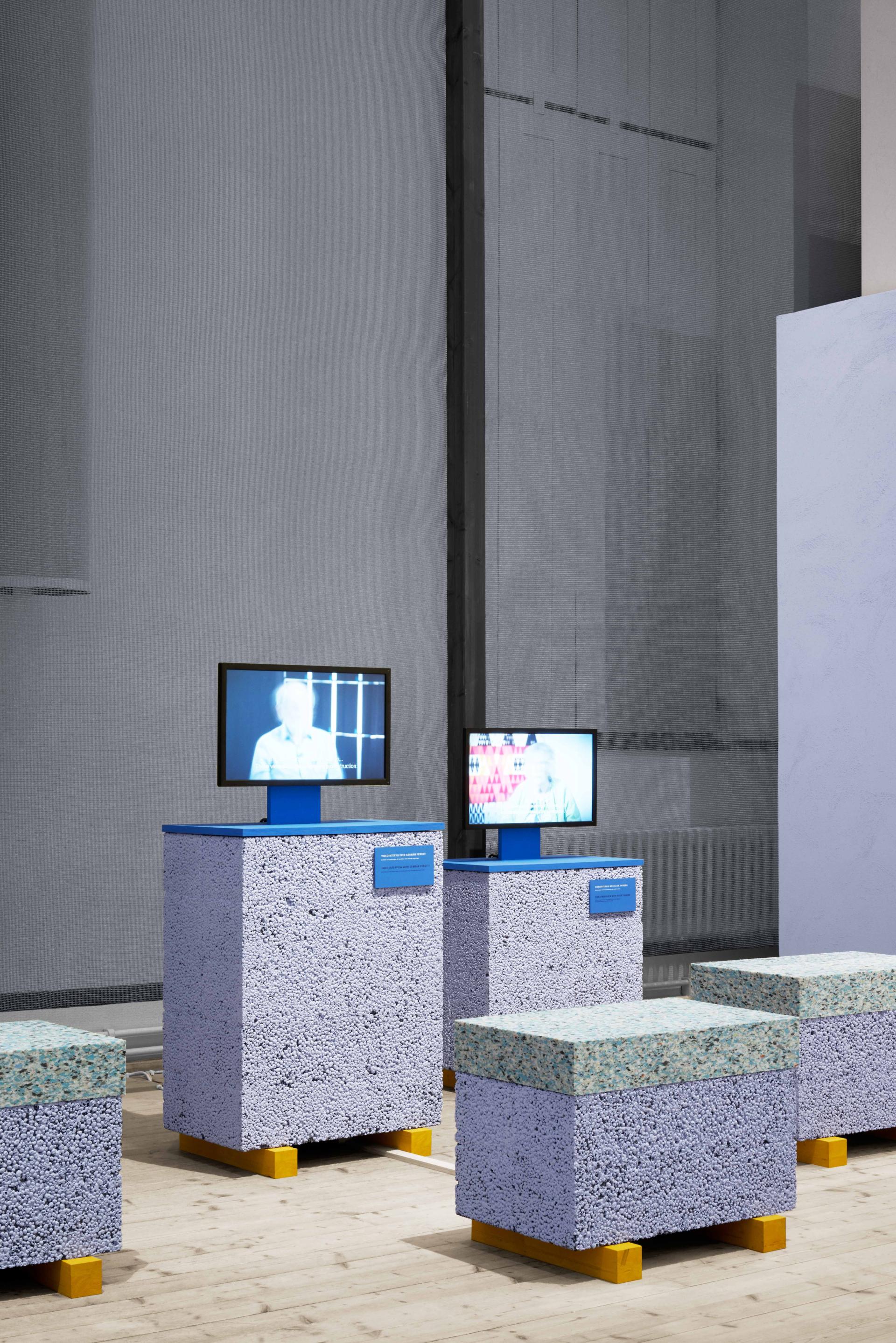 Interactive concrete display units with screens showcasing urban reconstruction themes at ArkDes, Stockholm.