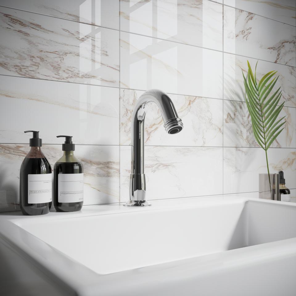 Stylish sensor tap above a modern sink with patterned tiles, featuring elegant soap dispensers and plant decor.