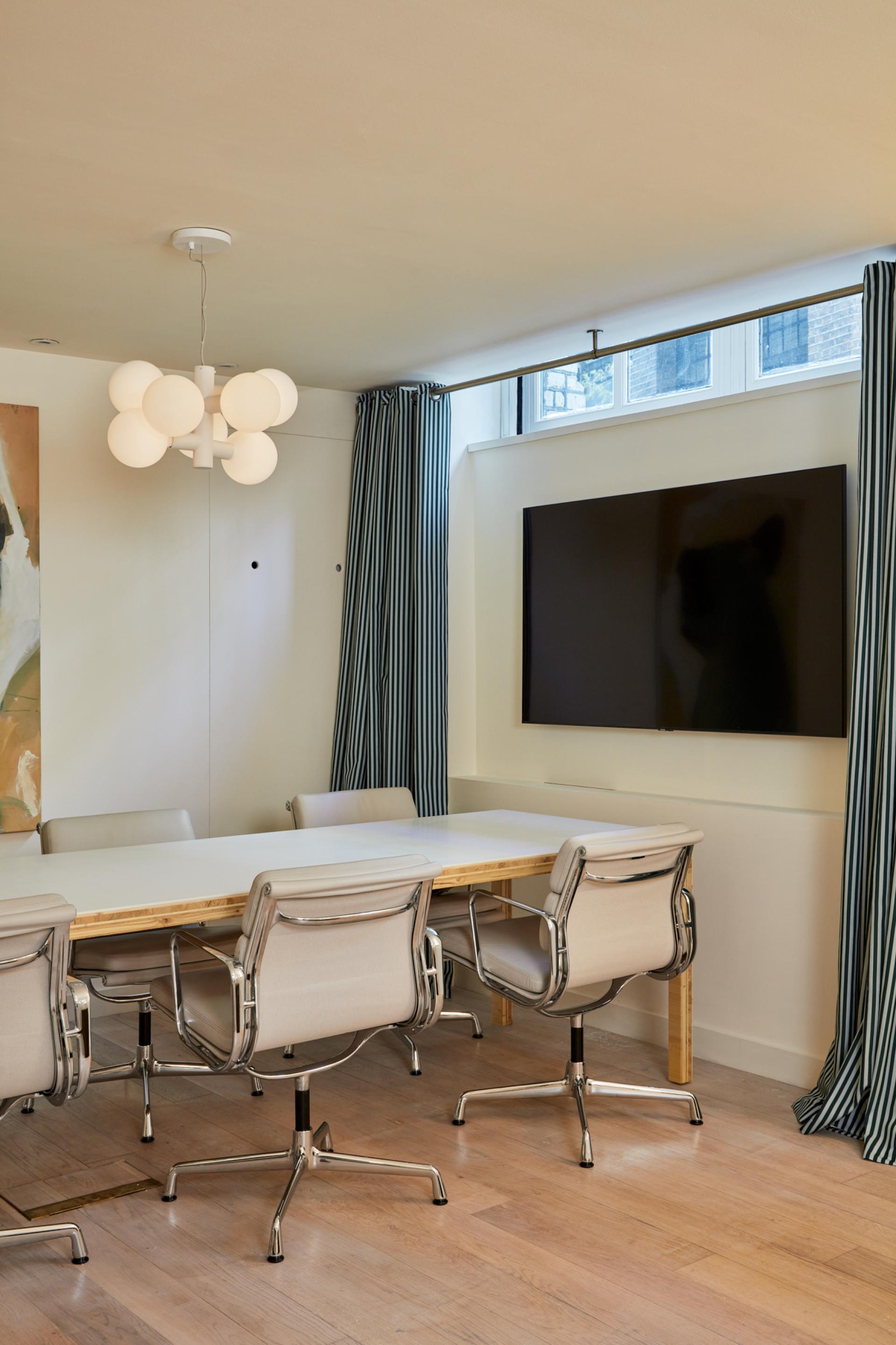 Modern Shoreditch showroom interior featuring a stylish lighting fixture, a long table, and contemporary decor.