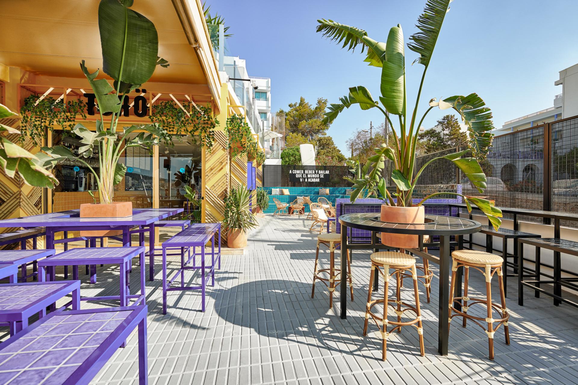 Vibrant outdoor seating area at Bar TORÖ in Ibiza, featuring Mediterranean-inspired design and tropical plants.