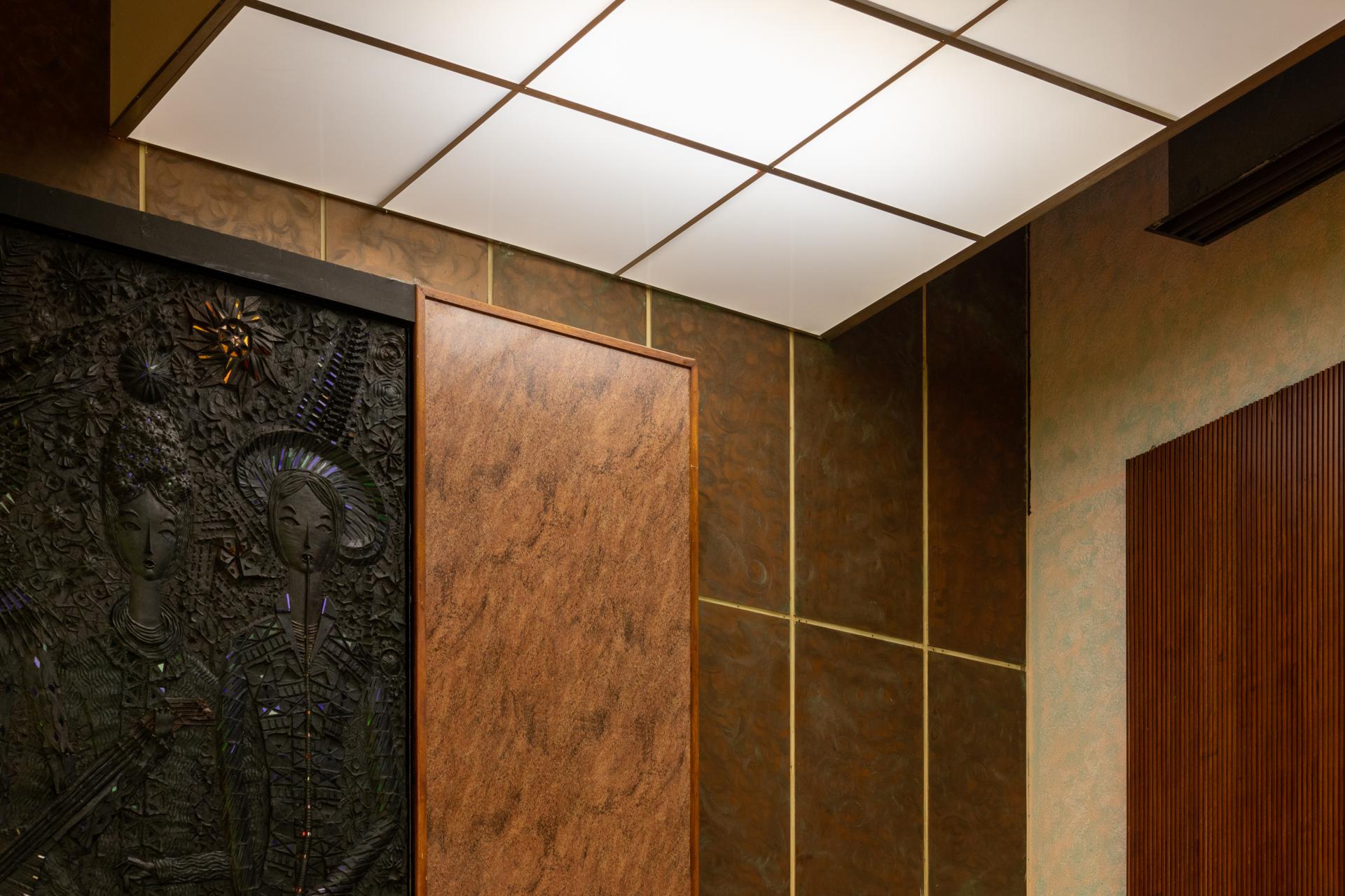 Interior detail of New Century venue showcasing artistic wall panels and textured surfaces, highlighting community-driven design.