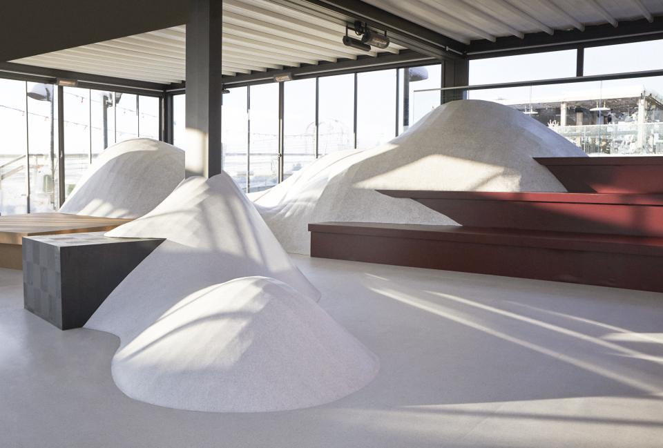 Exhibition space featuring flowing, snow-like shapes and sleek surfaces in a contemporary winter-themed design by Tarkett and Note Design Studio.