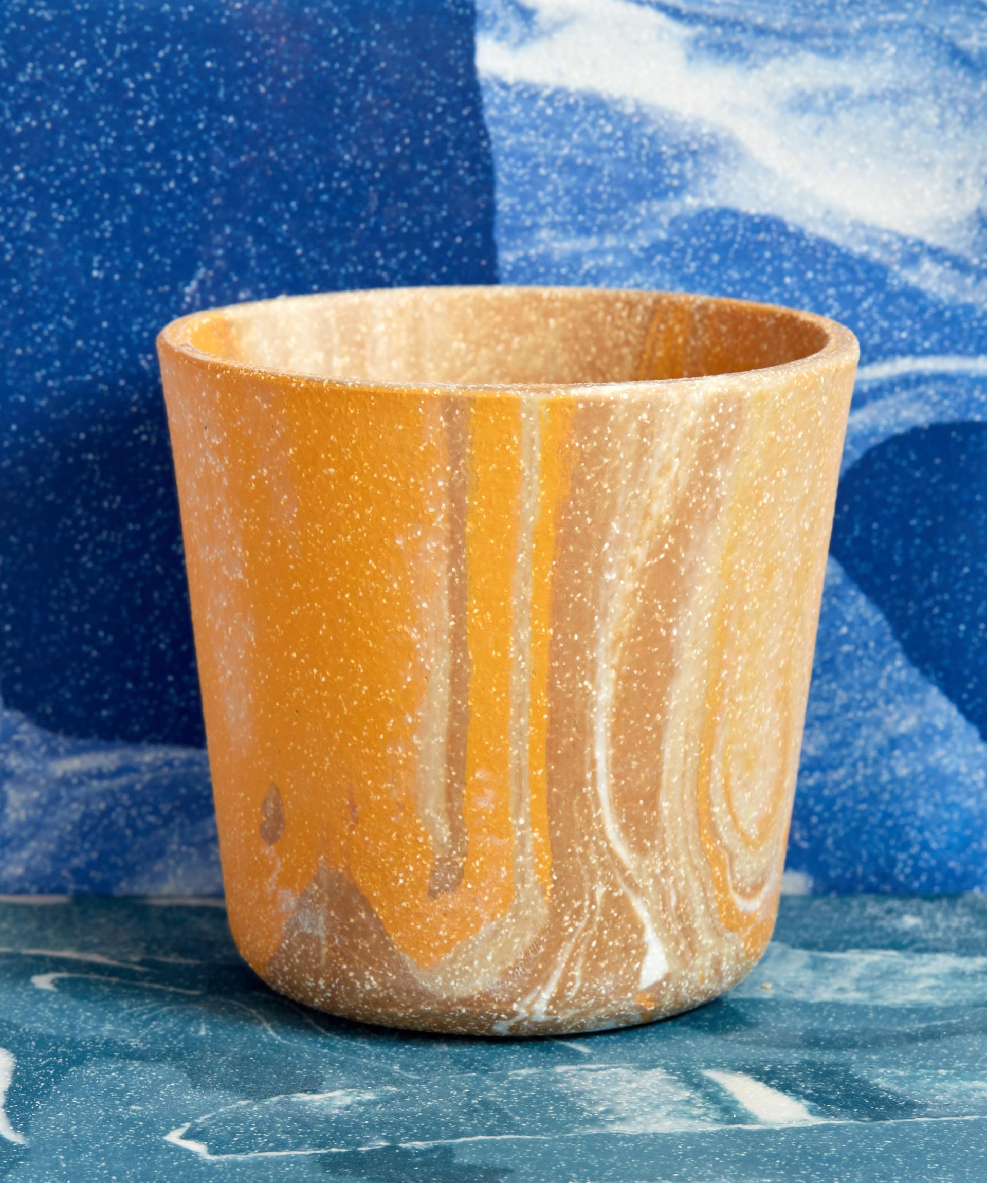 Bright orange marbled ceramic vessel set against a vibrant blue background, showcasing Granby Workshop's stylish tableware design.