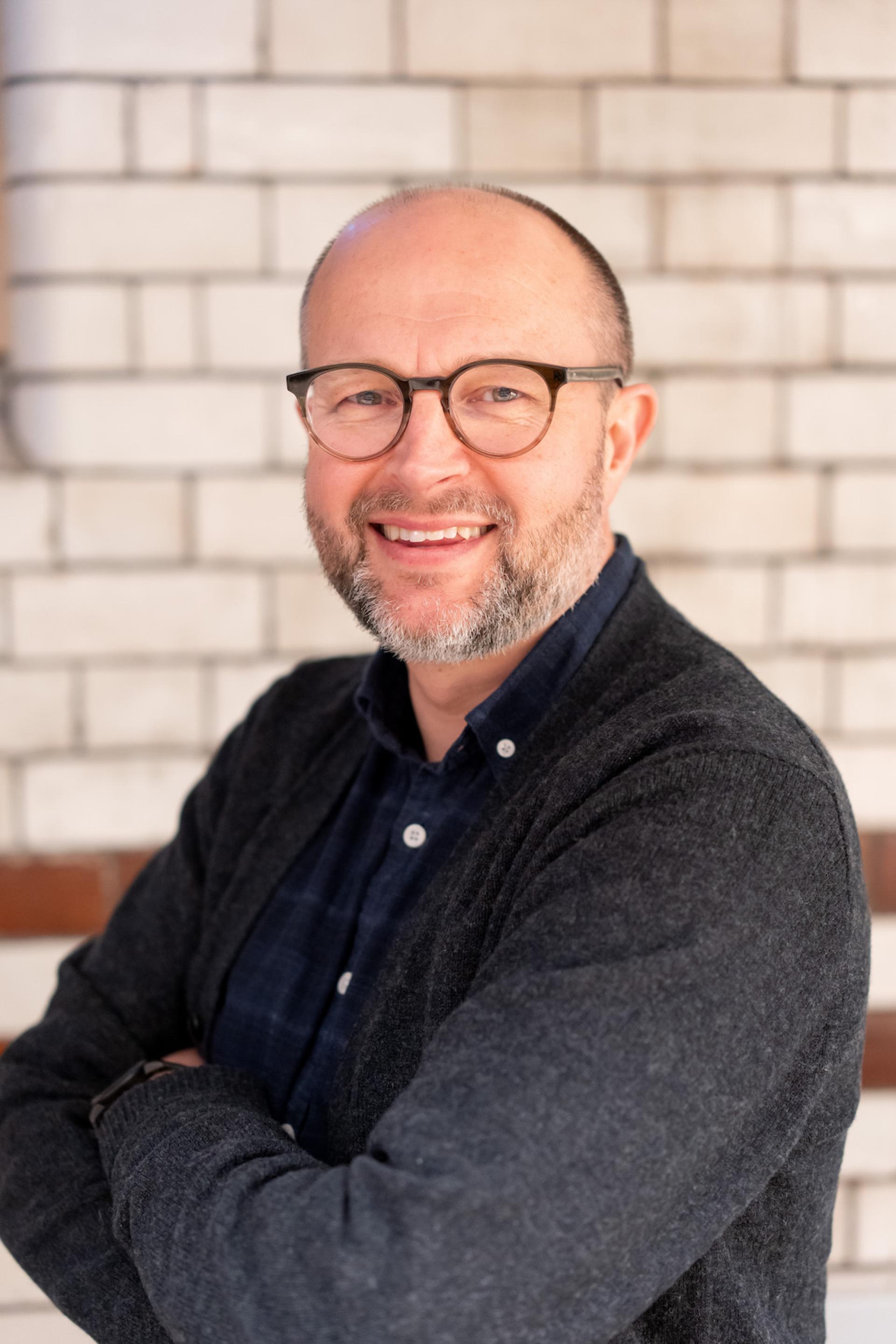 Professional man smiling in a cozy setting, discussing sustainability and value engineering at a roundtable event.