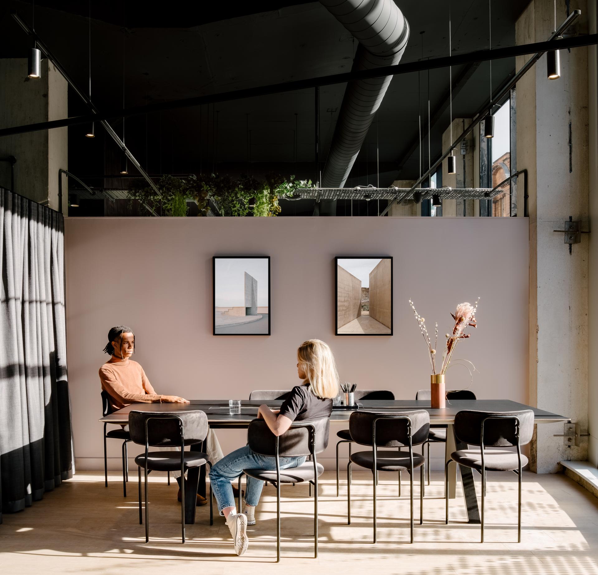 Modern co-working space featuring two people engaged in conversation, stylish design elements, and contemporary artwork on the walls.
