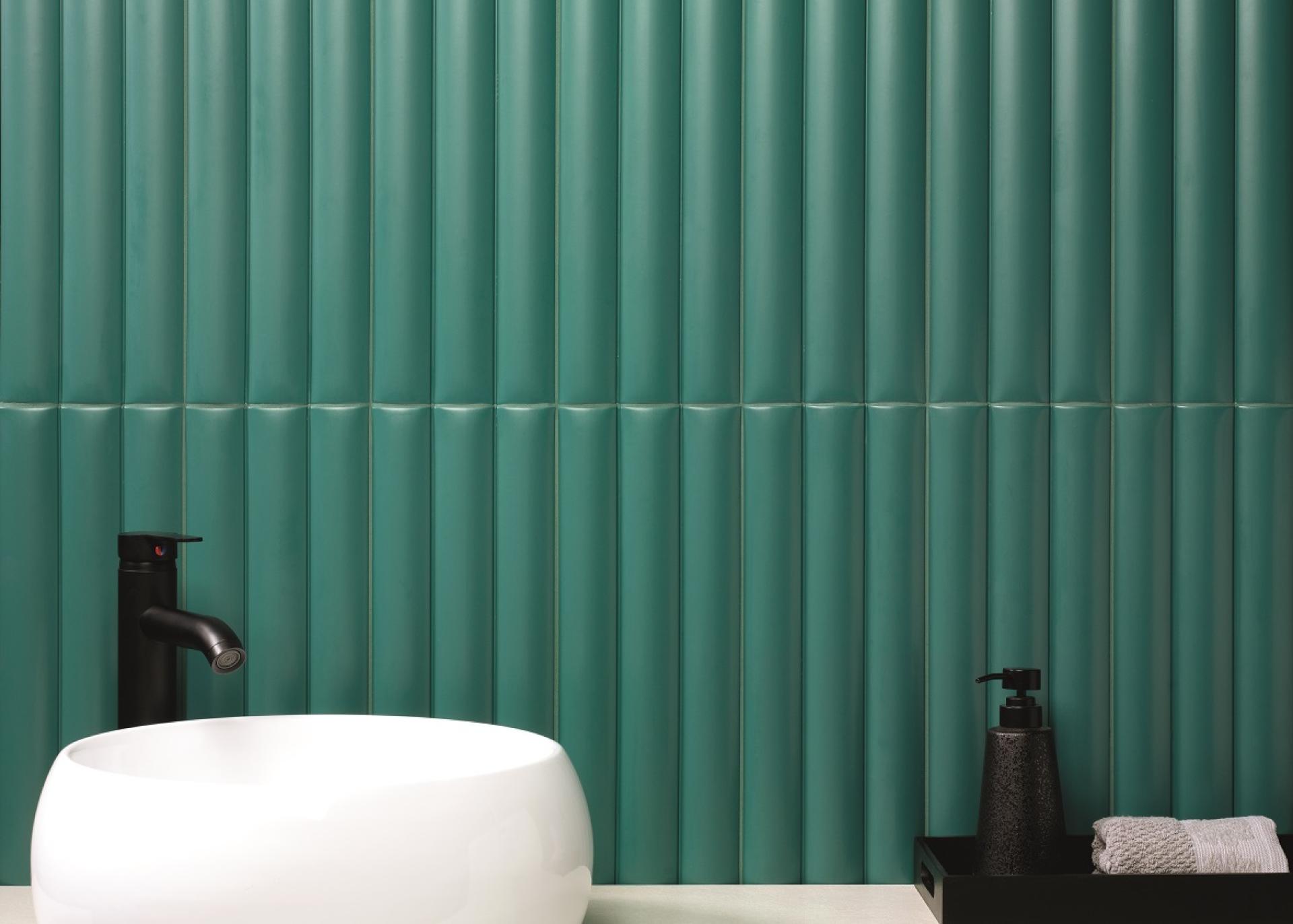 A modern bathroom design featuring textured teal tiles, a white basin, and stylish black accessories, emphasizing innovative tile materials.