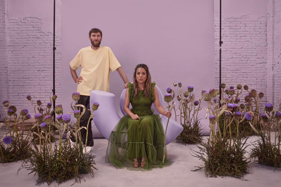 Three friends pose with artistic chairs and unique floral arrangements, showcasing creativity in furniture design by Mas Creations.