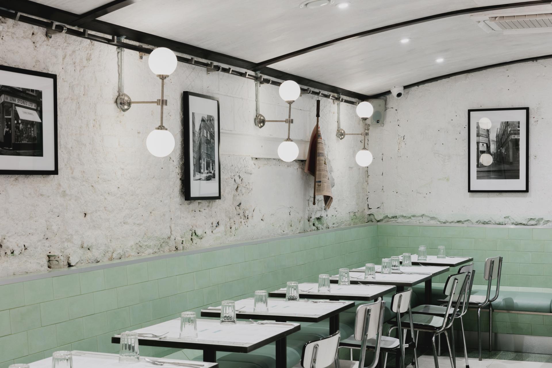 Art Deco-inspired Italian restaurant interior featuring green and white striped walls, vintage lighting, and elegant seating.