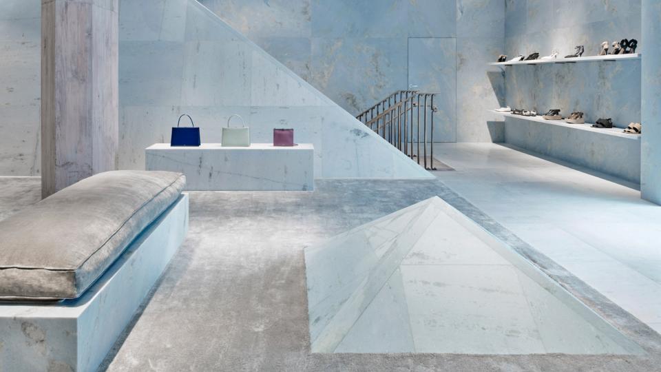 Céline store interior featuring blue marble surfaces, pyramid shapes, and elegant handbag displays designed by Valerio Olgiati.
