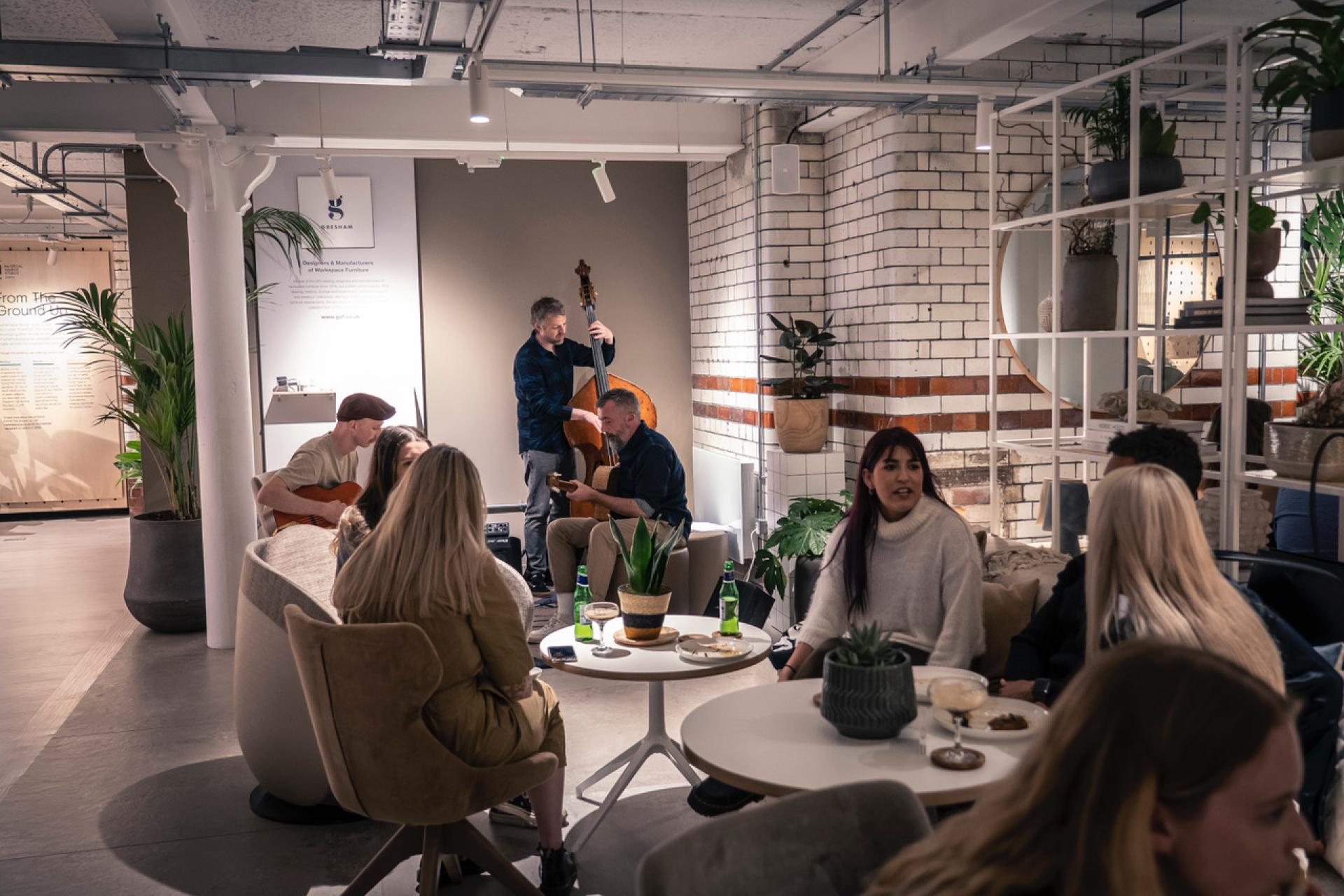 Attendees enjoying live music and conversation at the From The Ground Up exhibition celebrating biomimetic design.