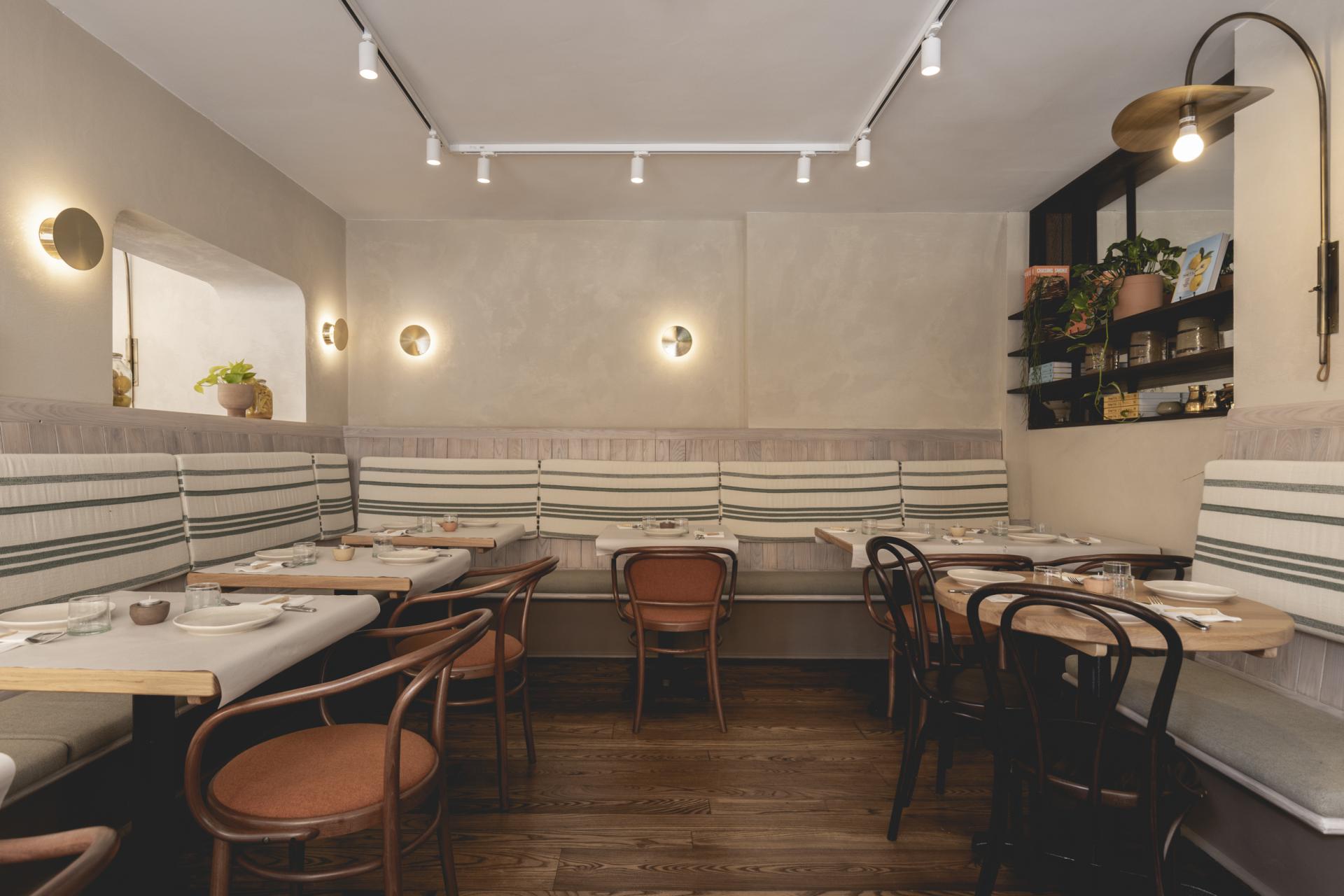 Cozy interior of Honey & Co Bloomsbury featuring elegant seating, wooden tables, and stylish lighting by Studio Found.