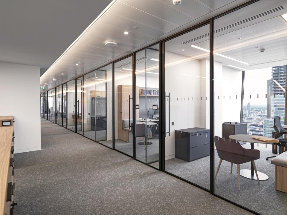 Modern office corridor featuring curved glass partitioning, showcasing Baker Botts' innovative workspace design by Radii.