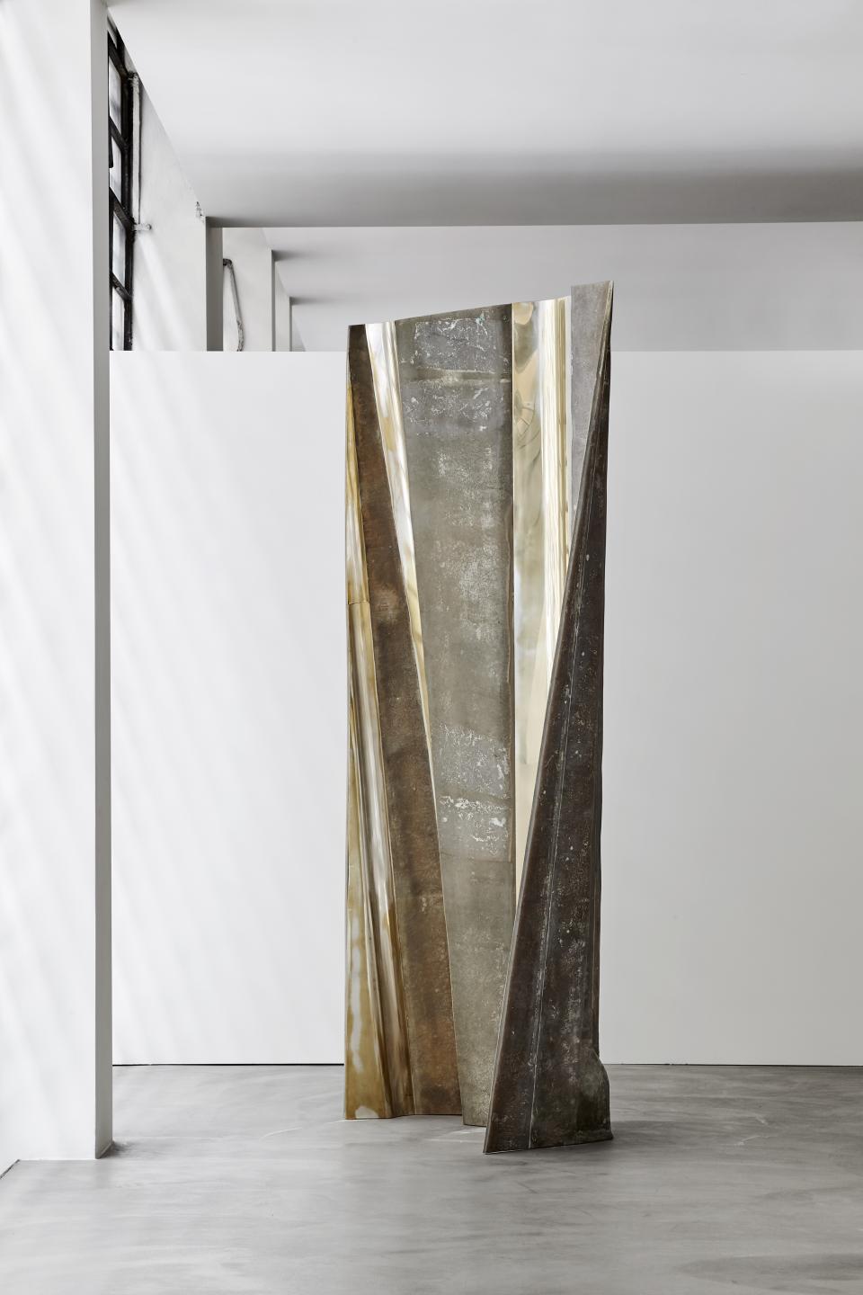 Sculptural furniture piece by Vincenzo de Cotiis, featuring metallic textures and geometric shapes in a minimalist gallery setting.