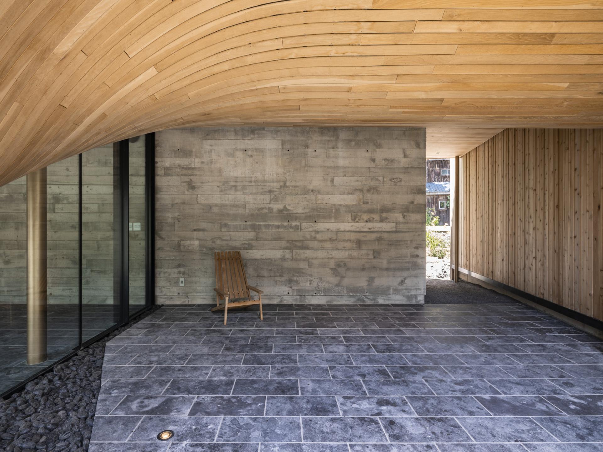 Modern interior of Fold House showcasing the curved wooden ceiling, polished concrete walls, and minimalist design elements.
