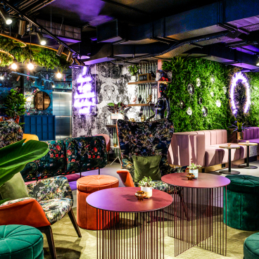 Stylish interior design at Qbic Hotel featuring bold floral upholstery, vibrant seating, and green wall accents by BOBO1325.