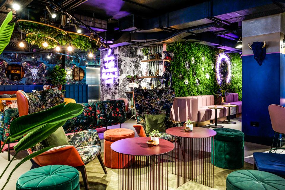 Stylish interior design at Qbic Hotel featuring bold floral upholstery, vibrant seating, and green wall accents by BOBO1325.