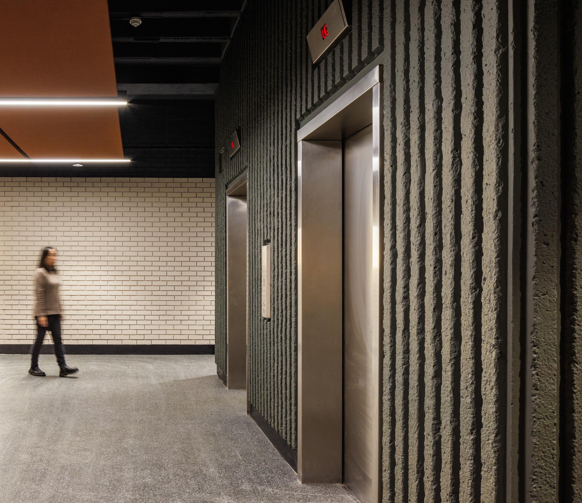 Modern interior of Stopford House featuring textured walls and elevators, highlighting SpaceInvader's brutalist design approach.