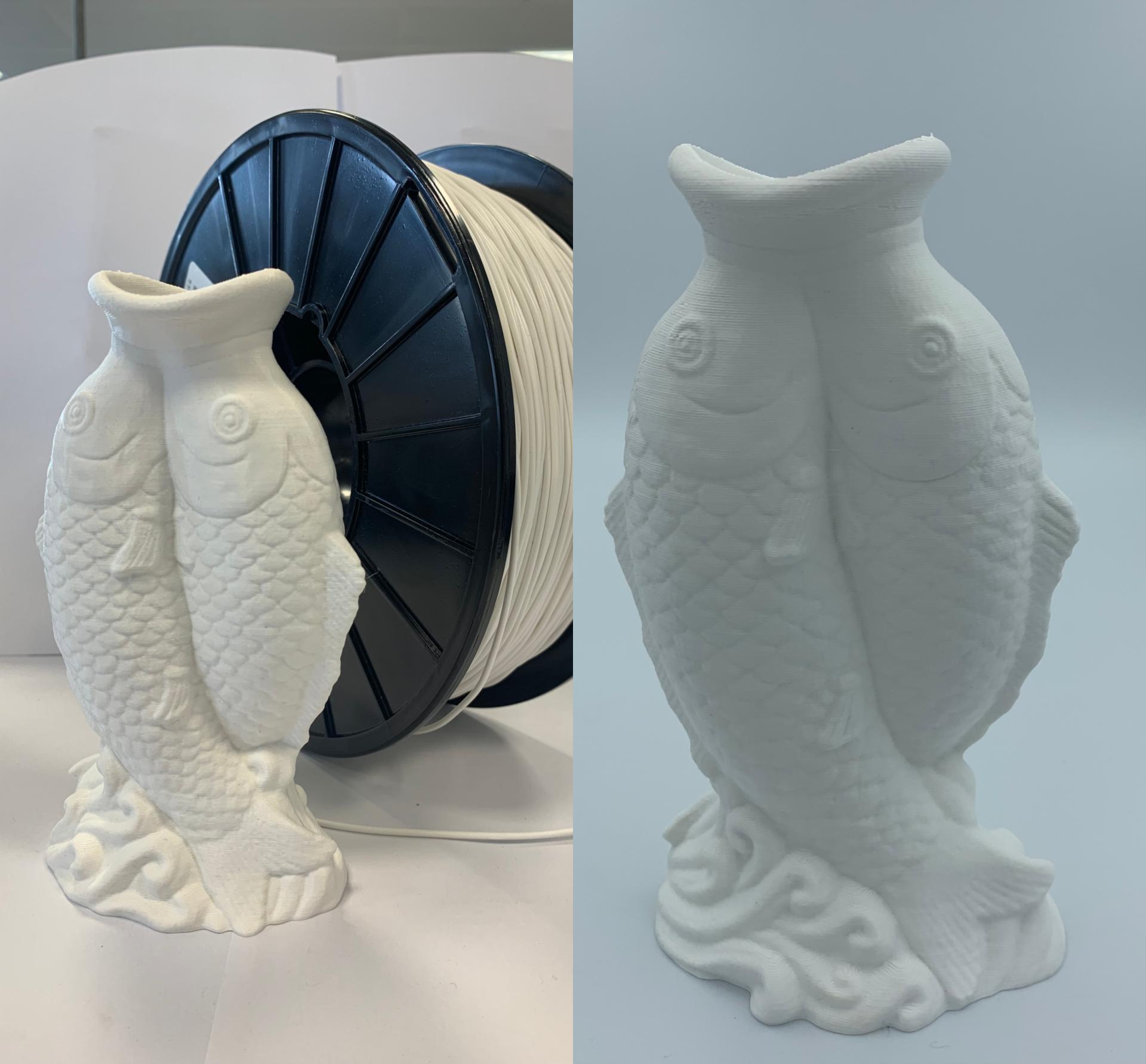 3D-printed sculpture of two fish made from post-consumer plastic filament, showcasing innovative recycling in manufacturing.