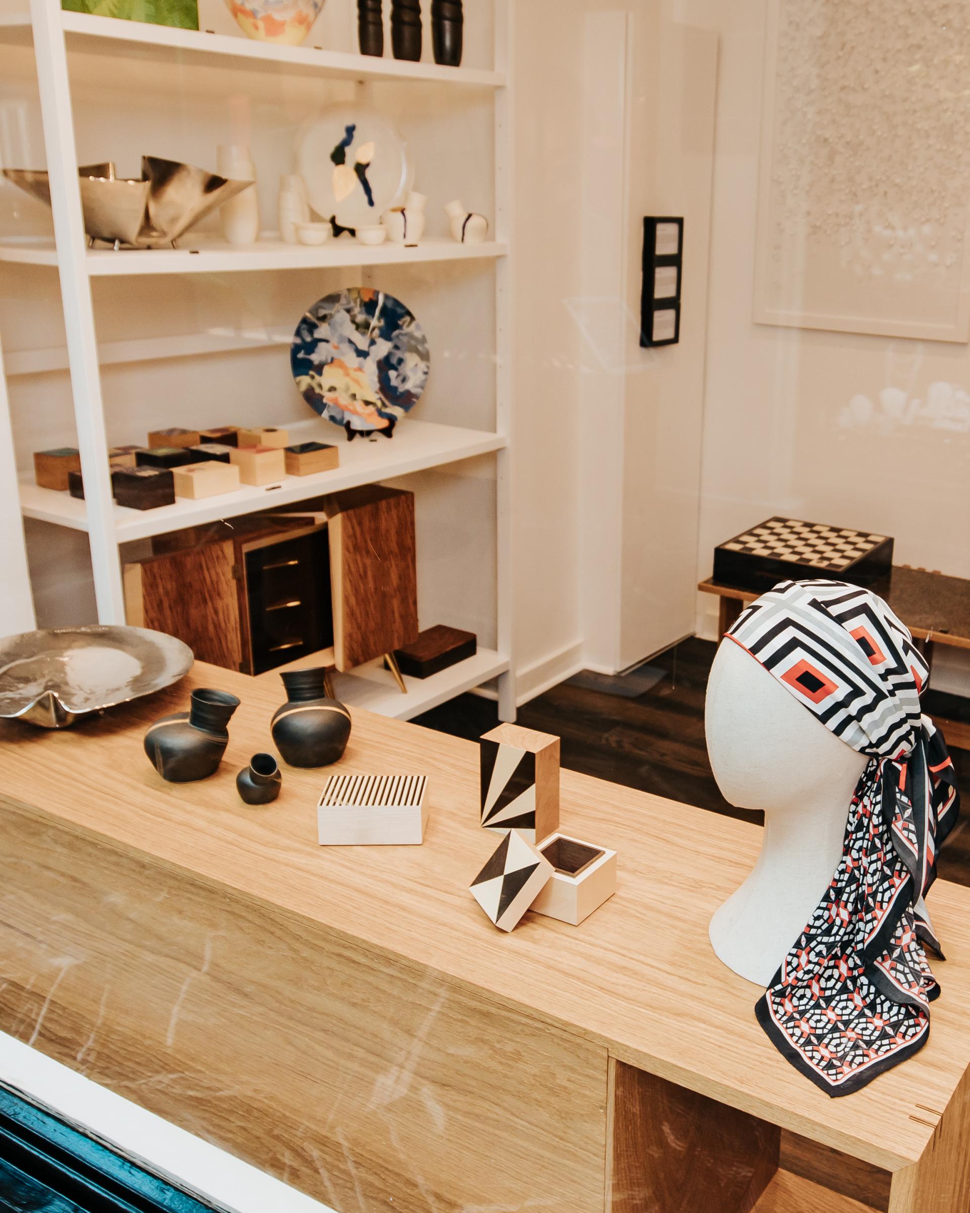 Contemporary design display featuring unique ceramics, wooden crafts, and a patterned scarf, highlighting Future Icons exhibition.