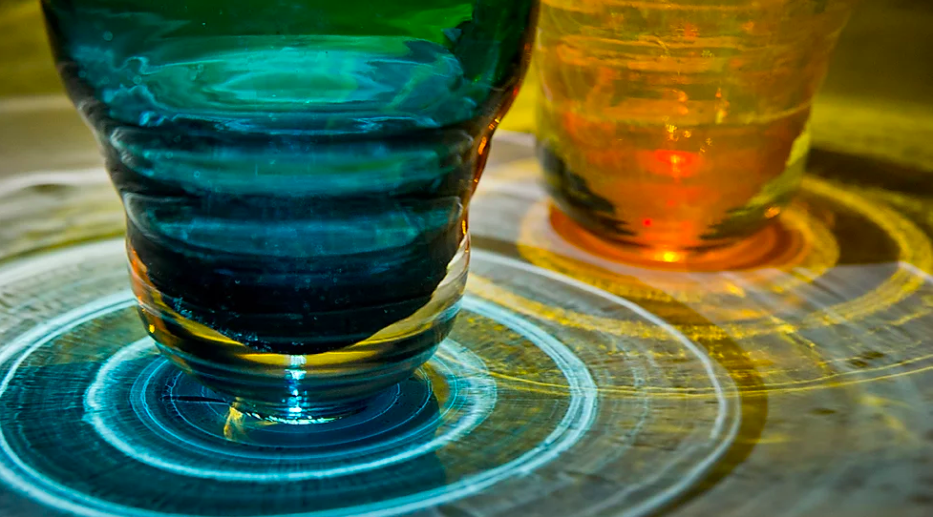 Colorful glass vases casting vibrant reflections on a wooden surface, highlighting Manchester's creative craft scene.
