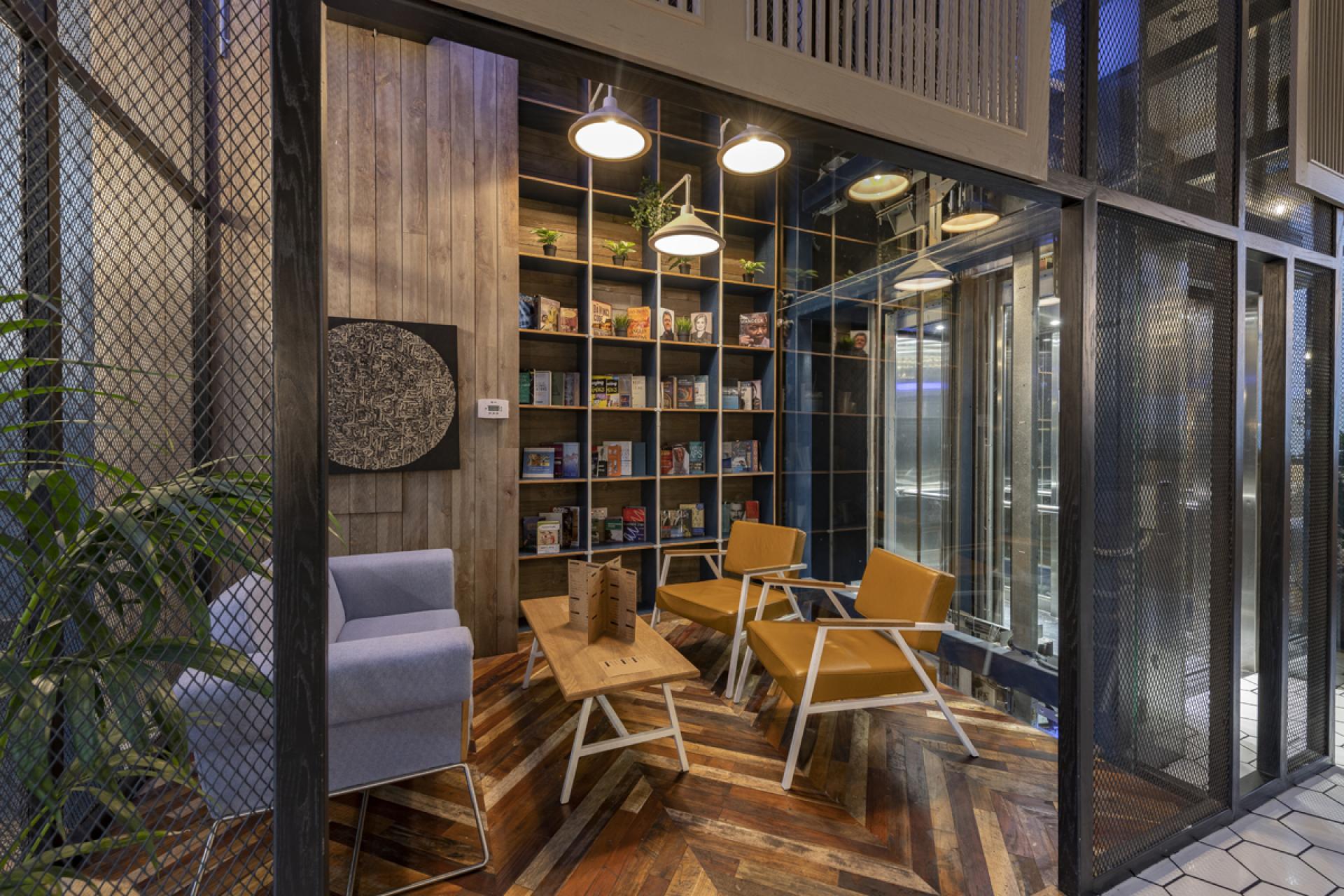 Contemporary seating area in Brew92 with a bookshelf, wooden flooring, and modern lighting by Liqui Design.