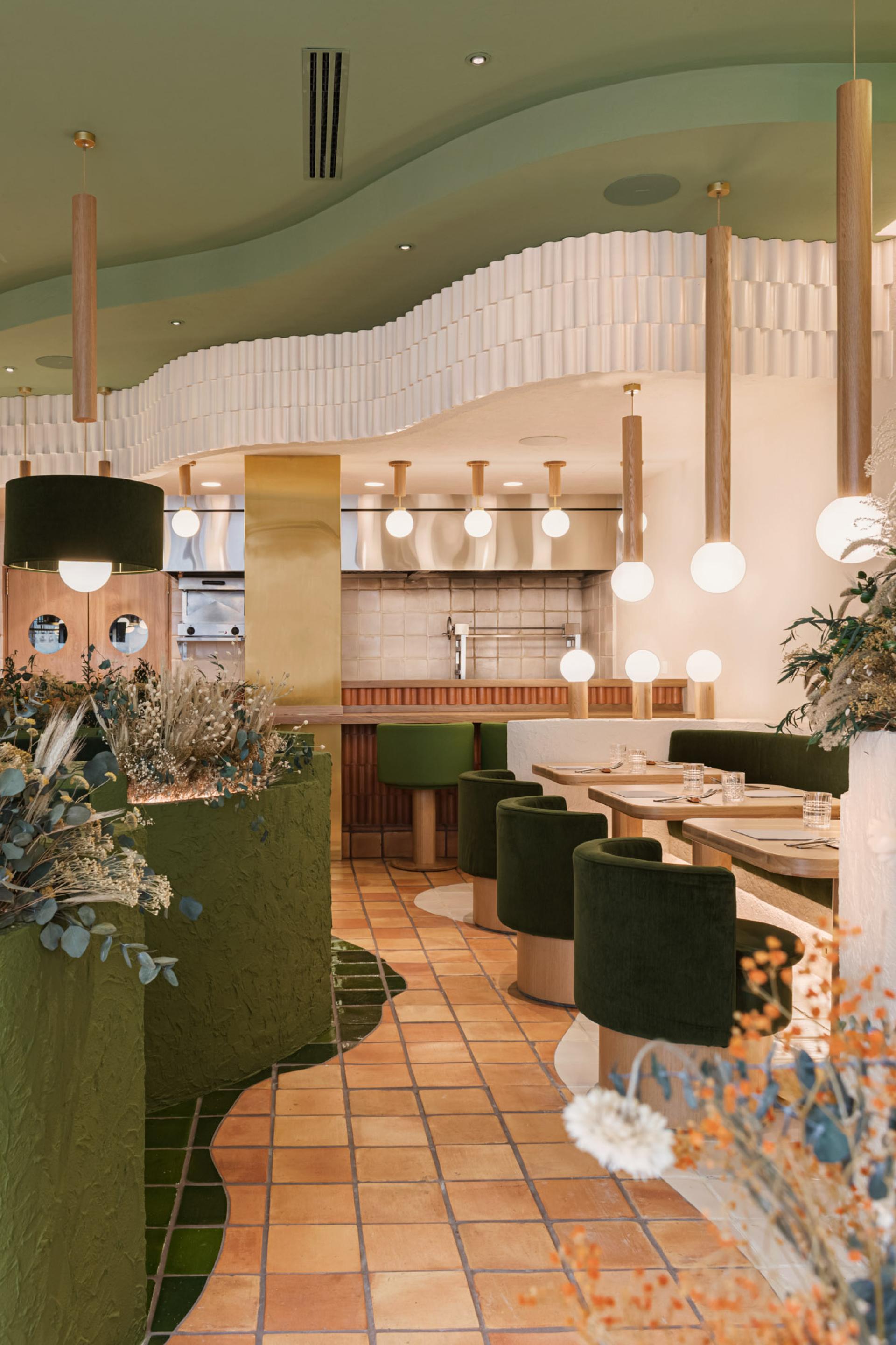 Modern restaurant interior designed by Masquespacio, featuring green accents, plant decorations, and a warm, inviting atmosphere.