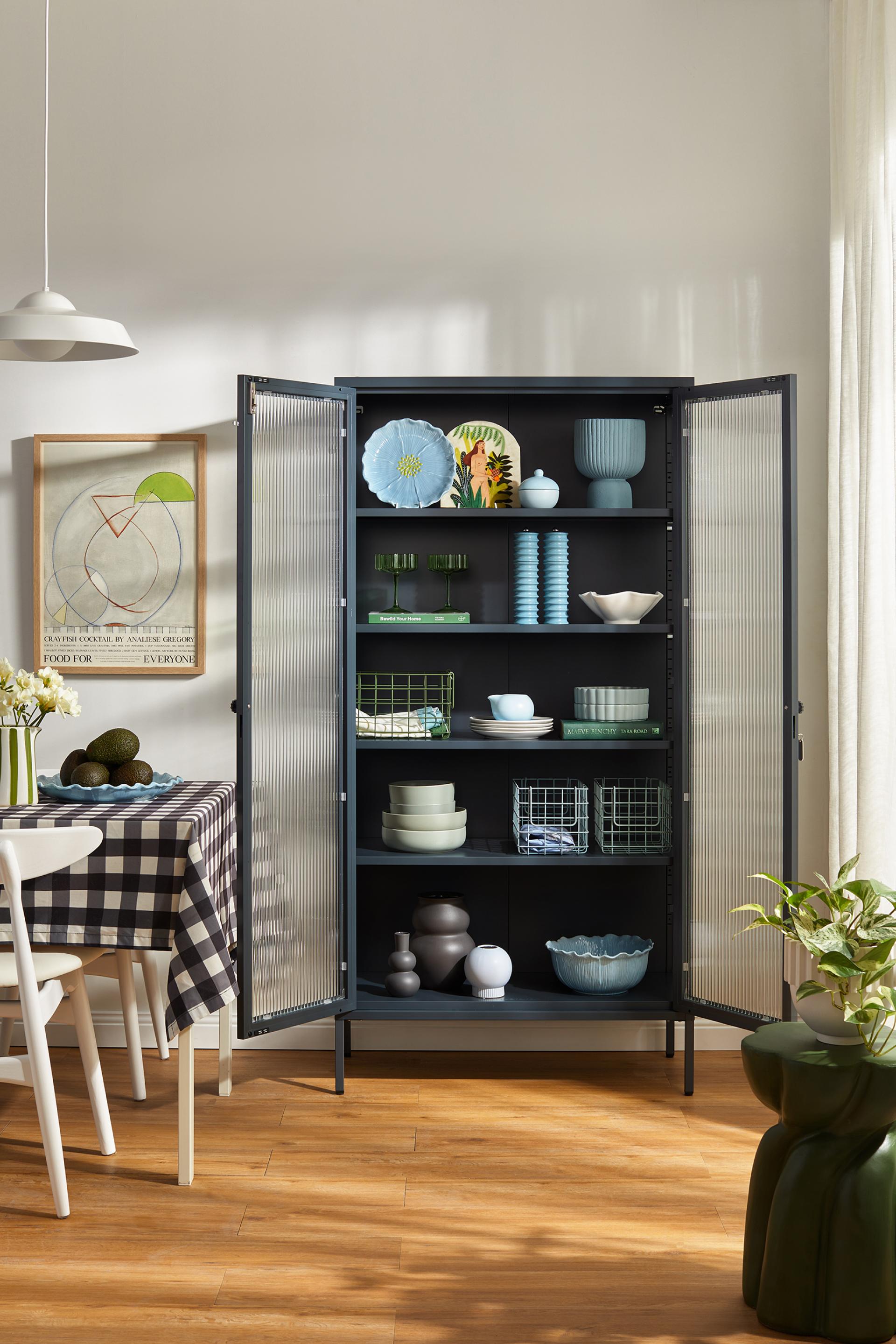 Stylish cabinet from Mustard Made's Glass Collection displaying colorful dishware and decorative items in a modern setting.