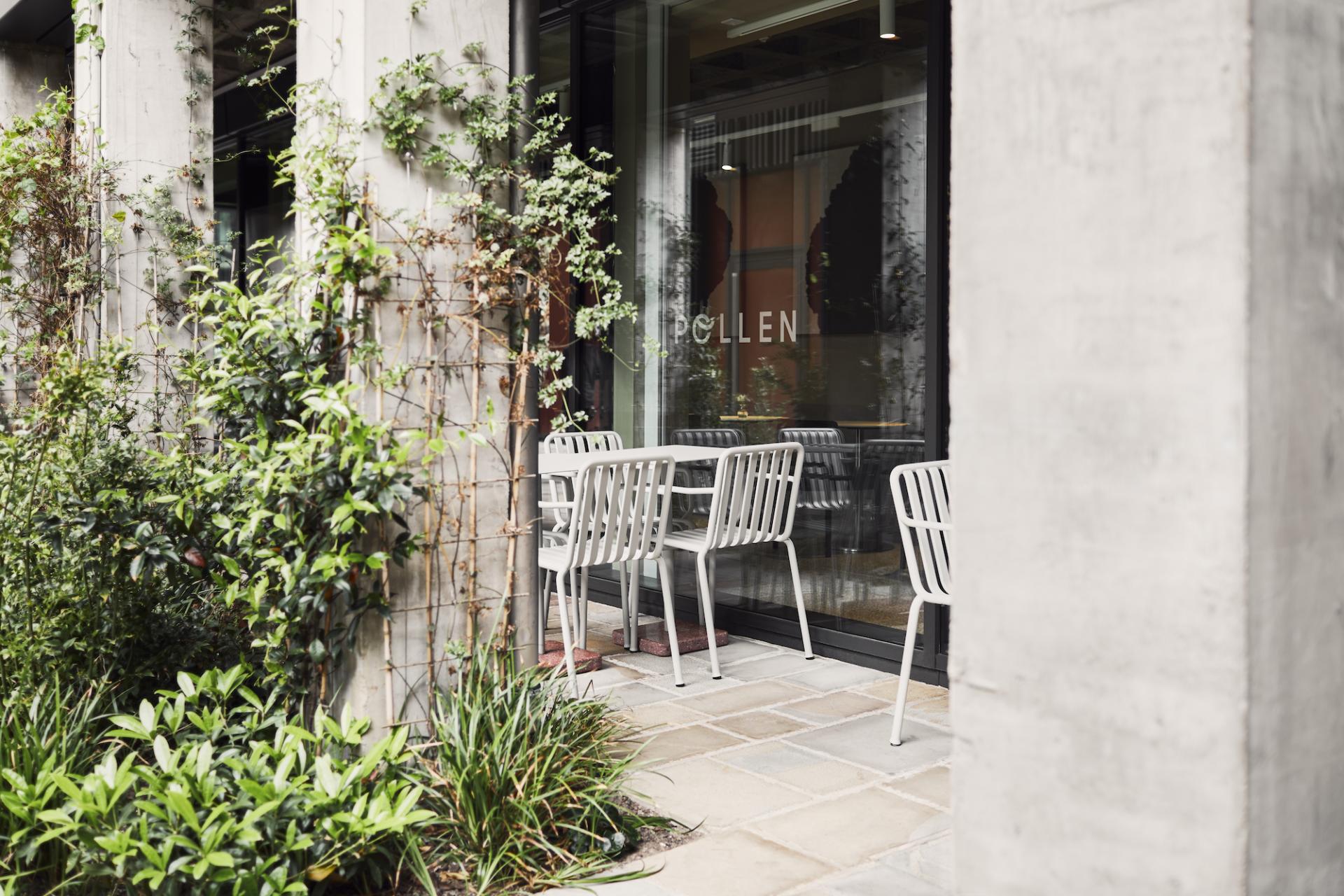Outdoor seating area of Pollen Bakery, featuring modern chairs and lush greenery, highlighting the café's inviting atmosphere.