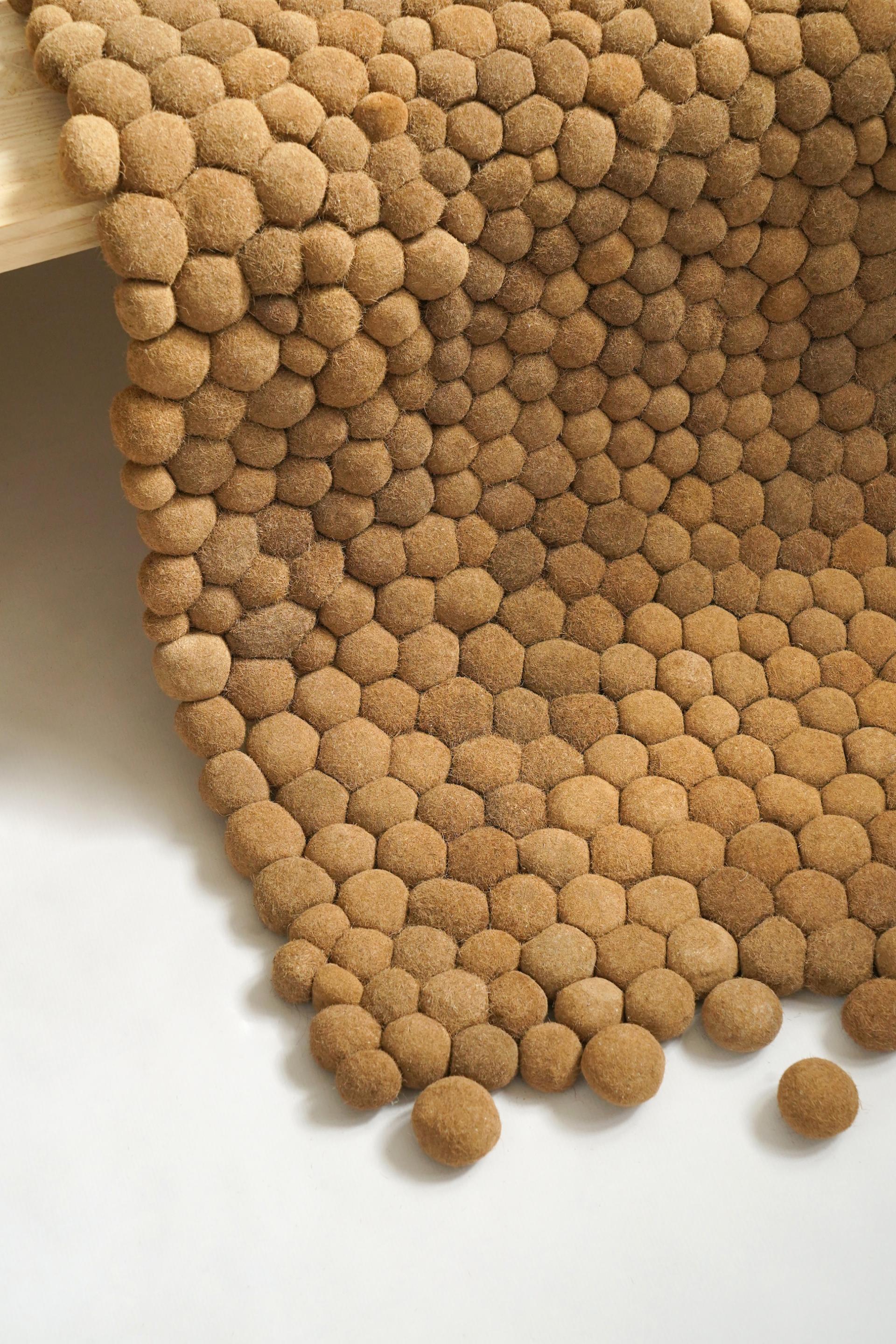 Textured rug made from natural Posidonia seagrass, showcasing hexagonal and circular patterns, highlighting sustainable design.