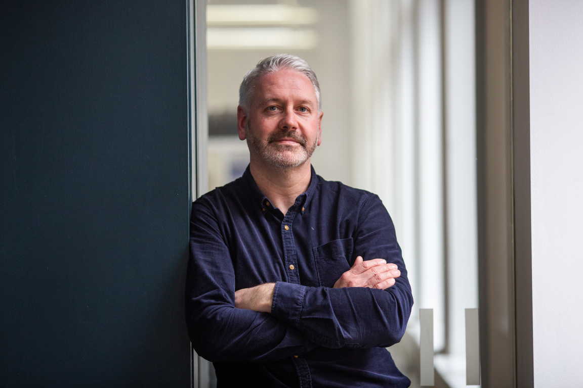 Scott Torrance, an architect at 3DReid, poses thoughtfully in a modern Glasgow office setting.