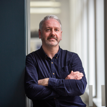 Scott Torrance, an architect at 3DReid, poses thoughtfully in a modern Glasgow office setting.