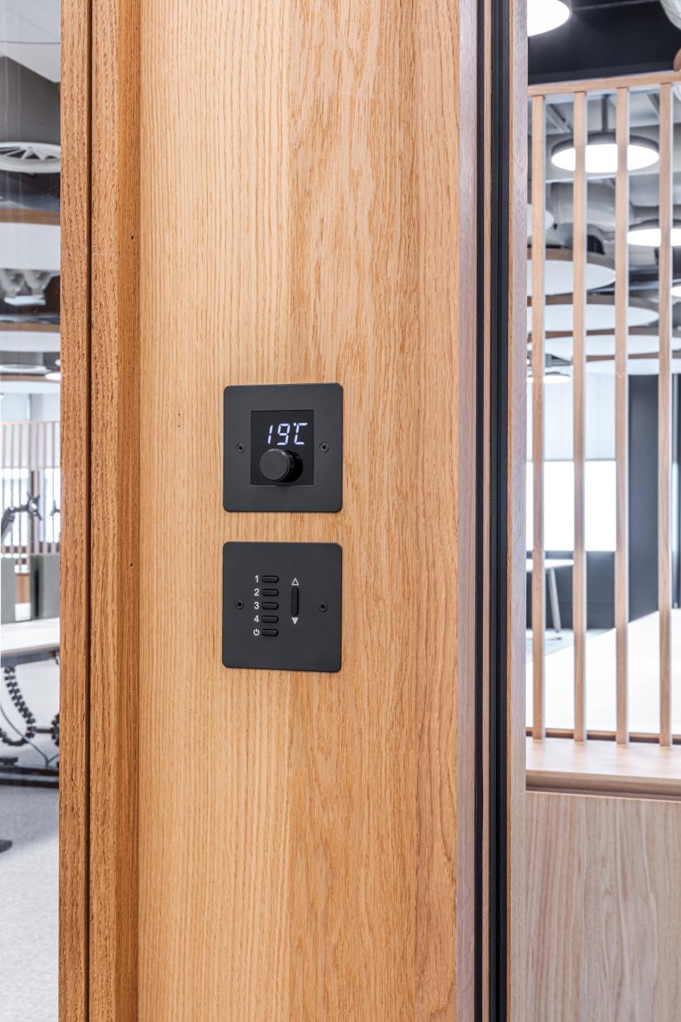 Timber-framed glazed partition features a digital thermostat and control panel at Boston Consulting Group's London office.