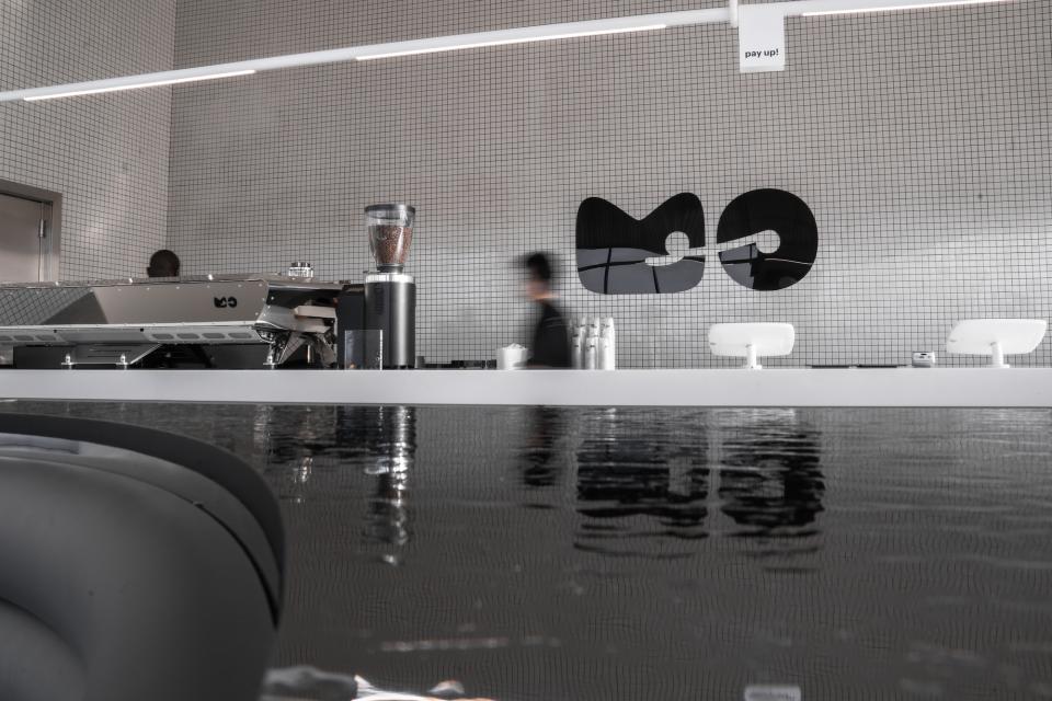 Modern espresso bar interior featuring sleek design elements, a coffee grinder, and branded signage for MO.