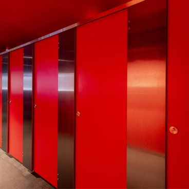 Vibrant red restroom stalls featuring sleek metal accents, highlighting the trend for stylish and 'Instagrammable' washroom designs.