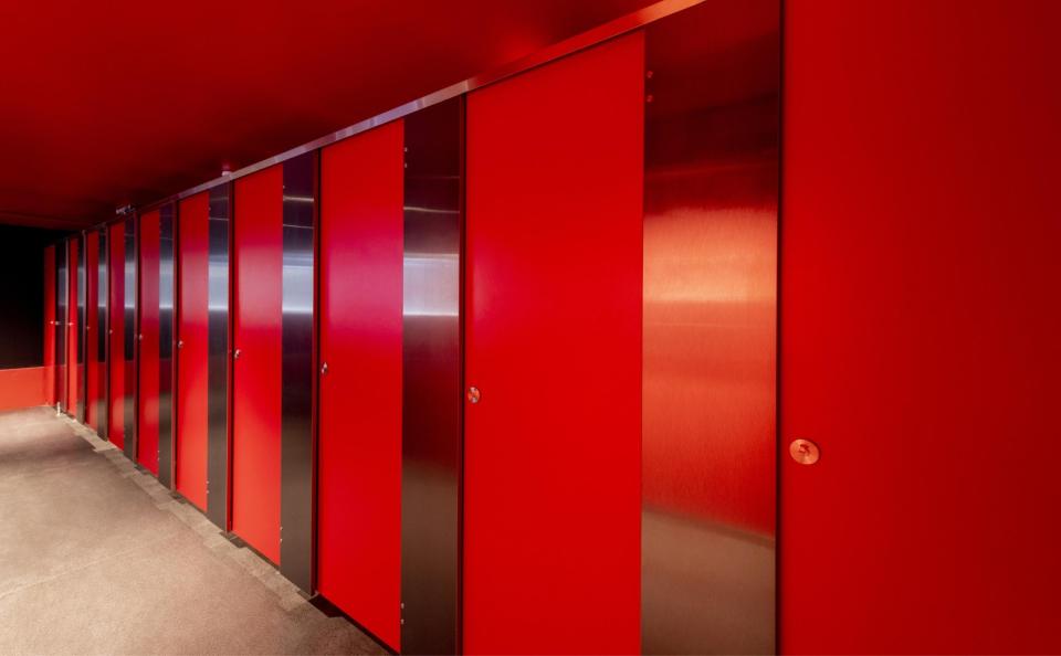 Vibrant red restroom stalls featuring sleek metal accents, highlighting the trend for stylish and 'Instagrammable' washroom designs.