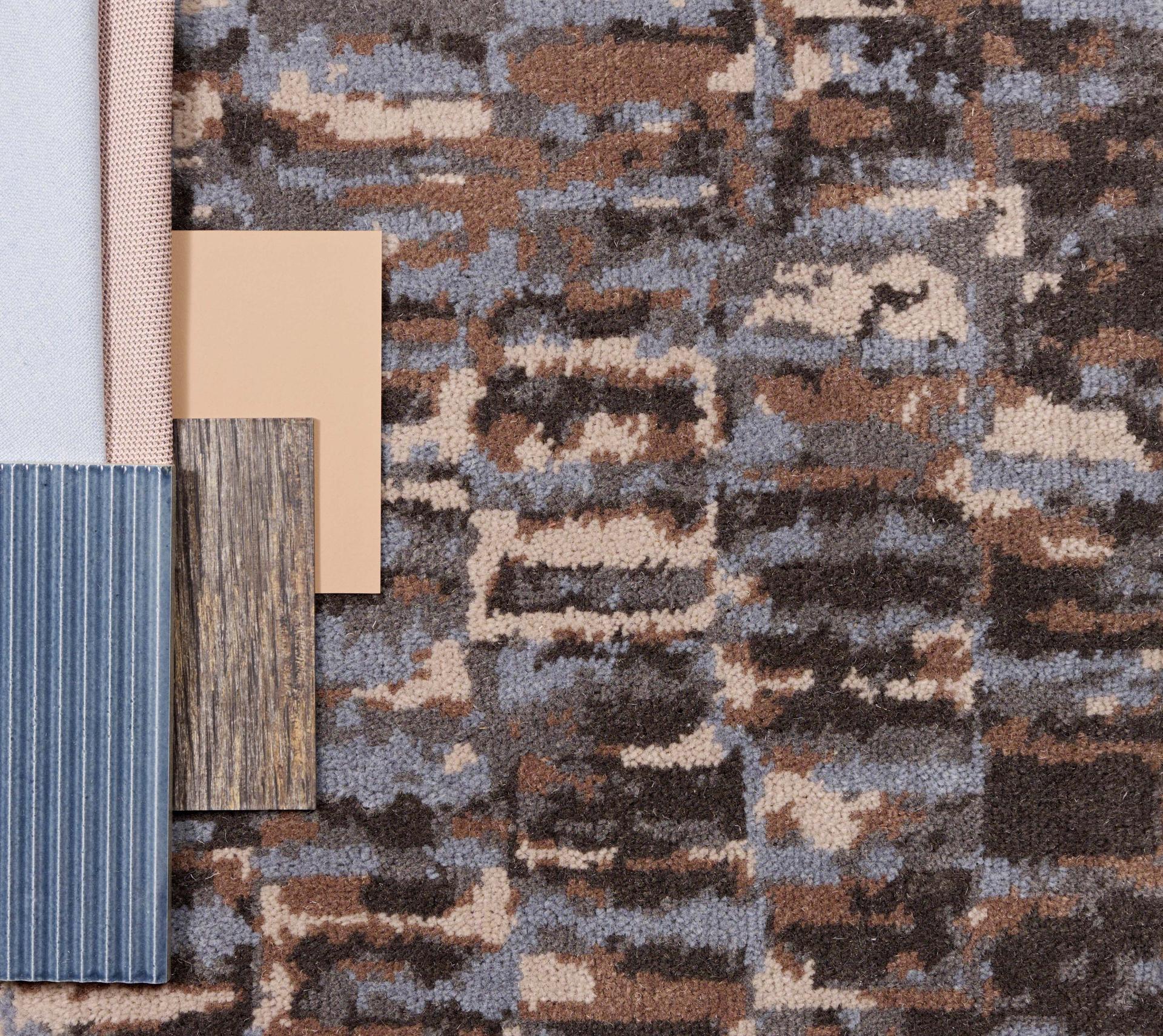Textured carpet swatch with brown and blue hues alongside fabric and material samples, reflecting Newhey's Elements collection.