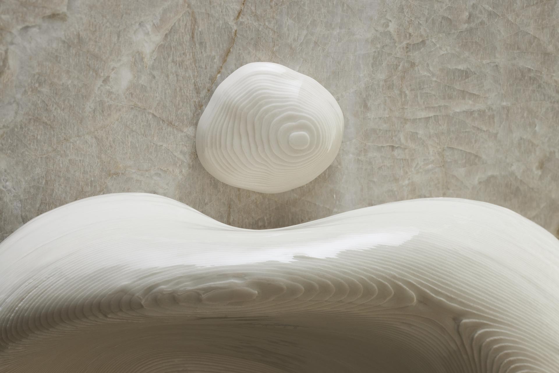 3D-printed Kohler sink designed by Daniel Arsham, featuring smooth white surfaces and organic shapes on a stone background.