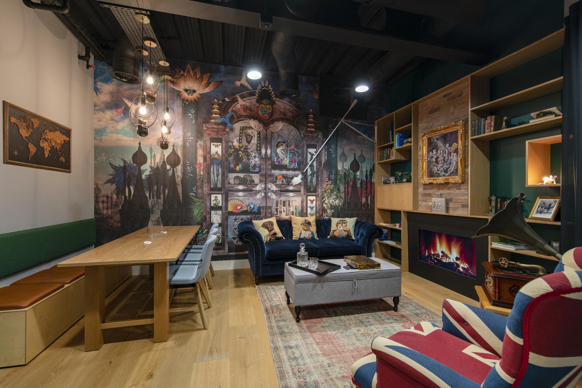 Stylish workplace design featuring a cozy lounge area with colorful artwork, a wooden table, and contemporary furnishings.