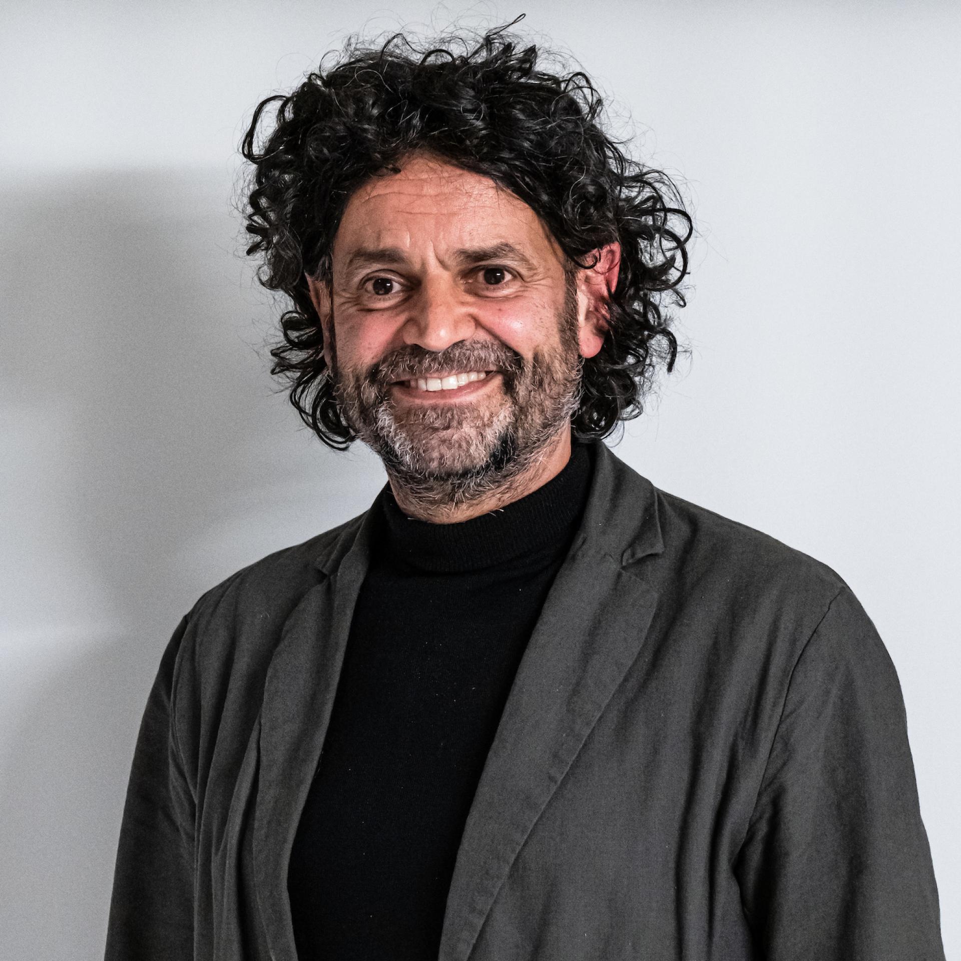 Professional man with curly hair smiles in a modern workspace, reflecting Manchester's dynamic property and co-living sector.