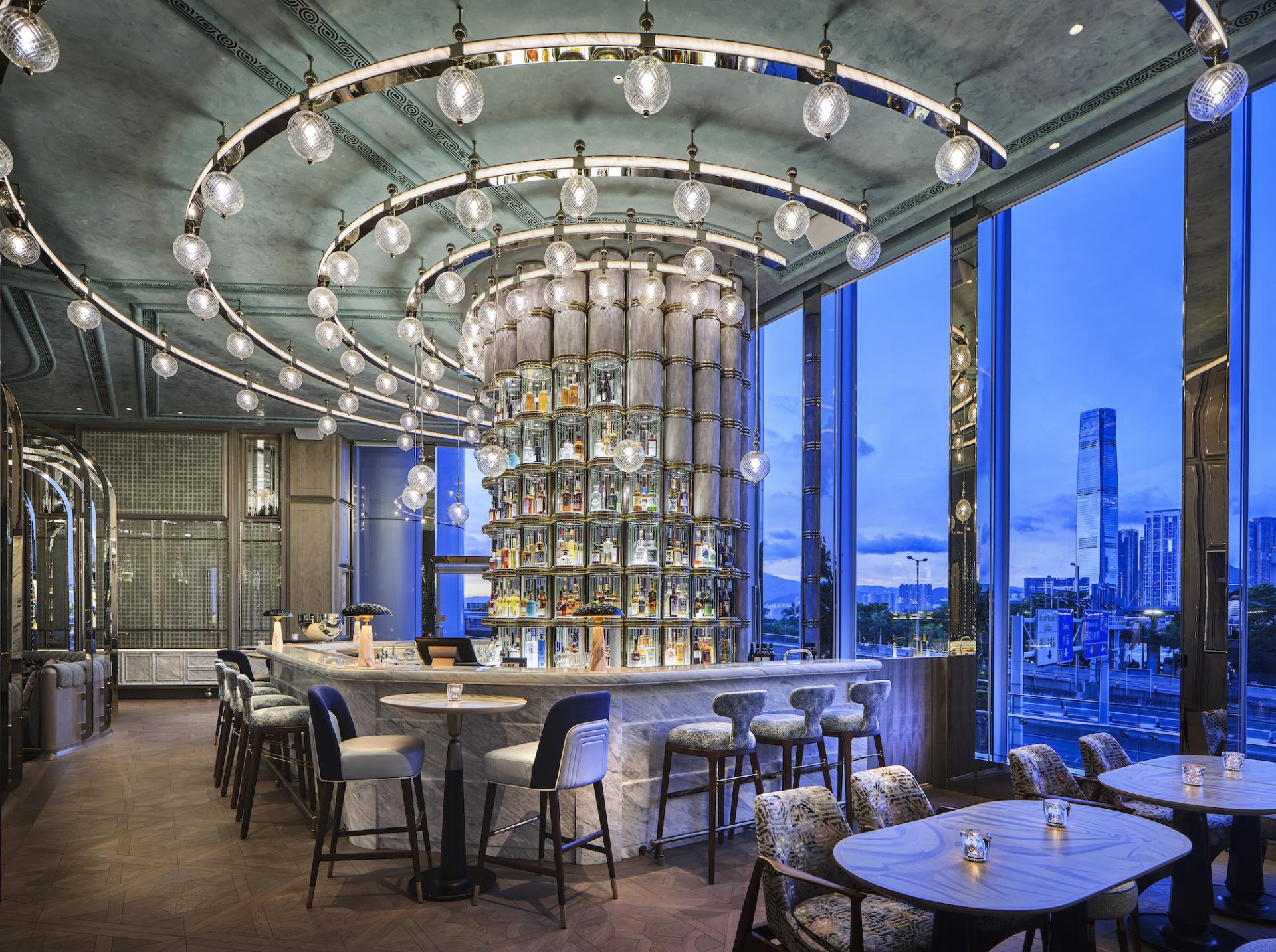 Elegant cocktail bar design at Four Seasons Hong Kong featuring a stunning light fixture and panoramic city views.