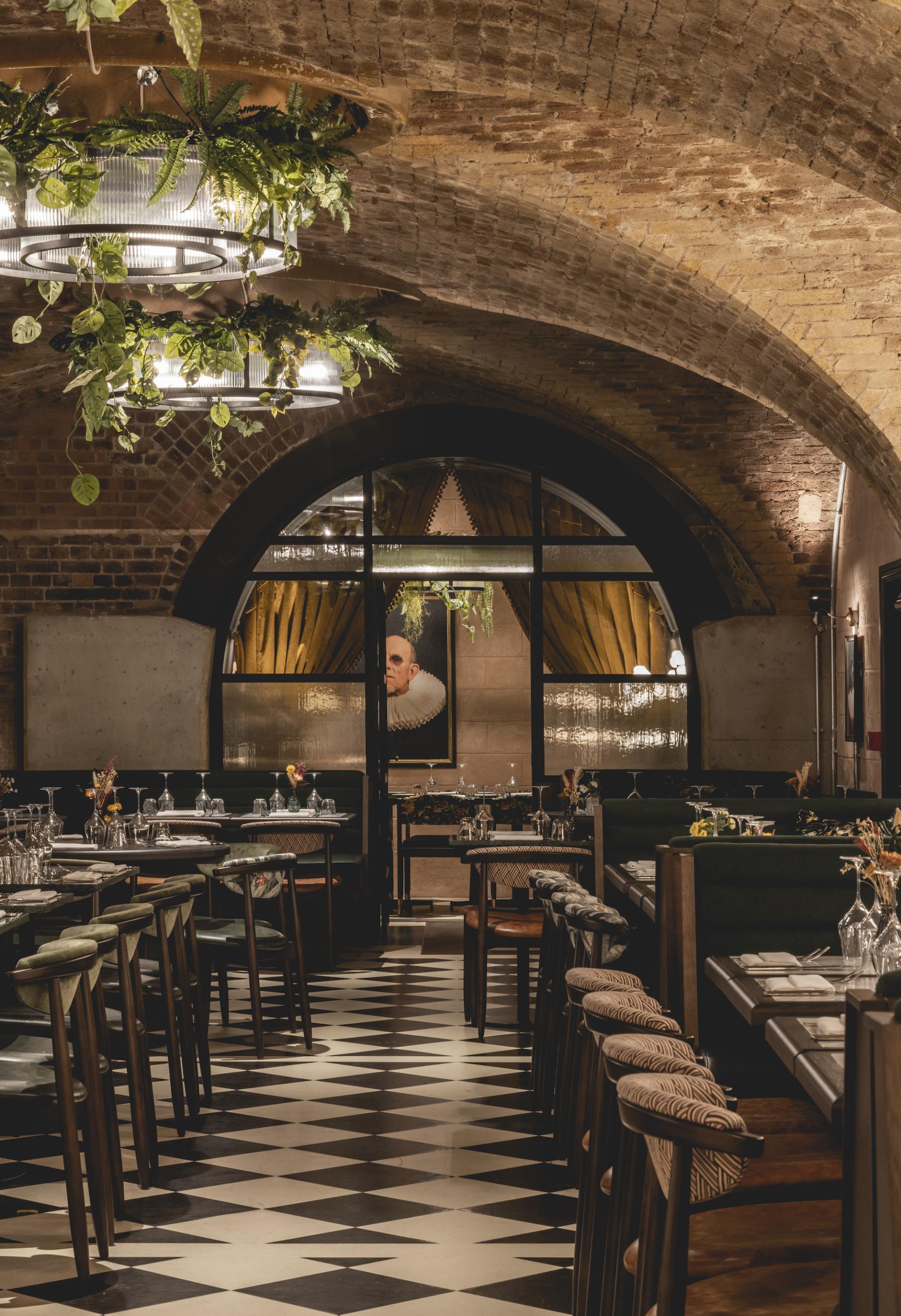 Elegant dining area of The Libertine in the Royal Exchange, featuring plants and a stylish, contemporary design.