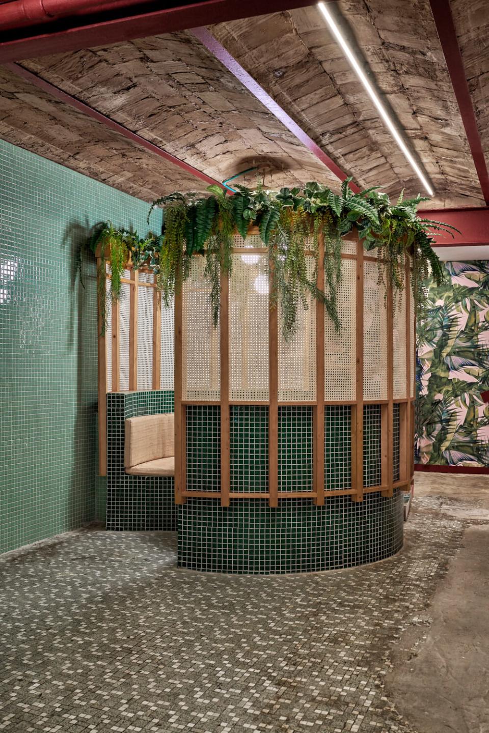 Lush green interior featuring bamboo seating and tropical plants, designed by Masquespacio for Valencia's tropical sushi restaurant Kaikaya.