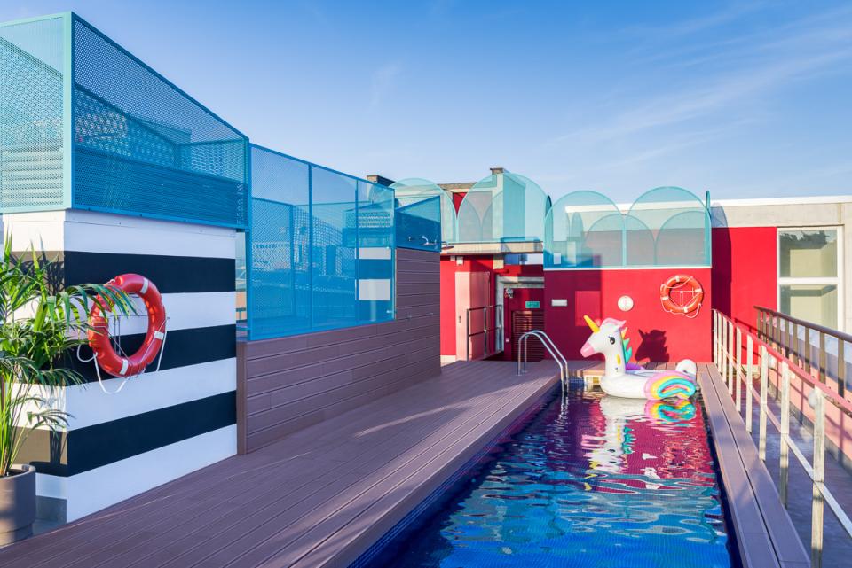 Colorful rooftop pool area at The Student Hotel Barcelona, featuring a unicorn float and vibrant design elements.