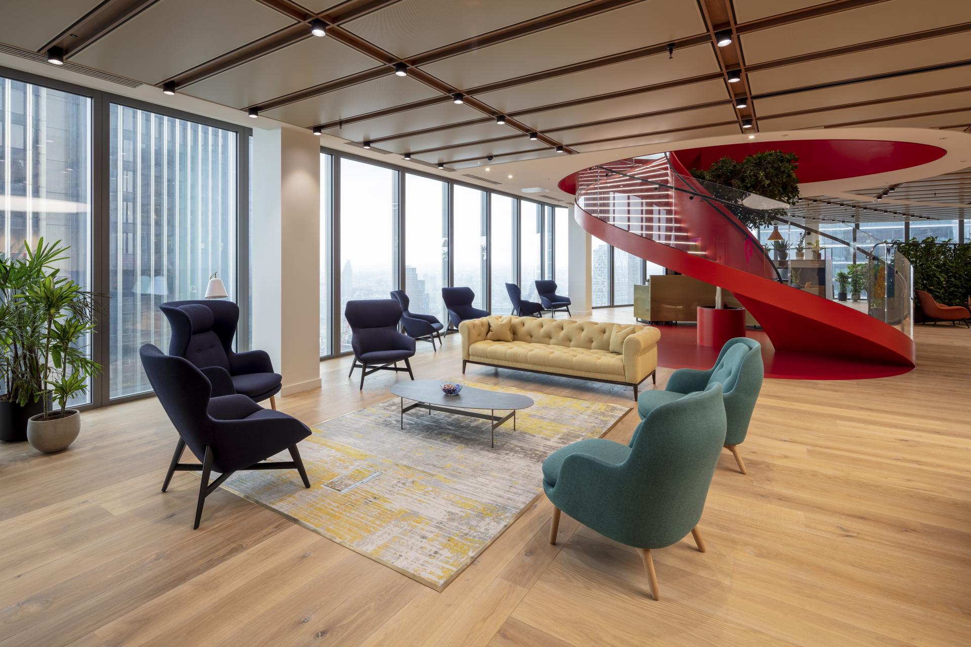 Modern office lounge with stylish furniture, vibrant colors, and panoramic windows at Canopius' new London skyscraper.
