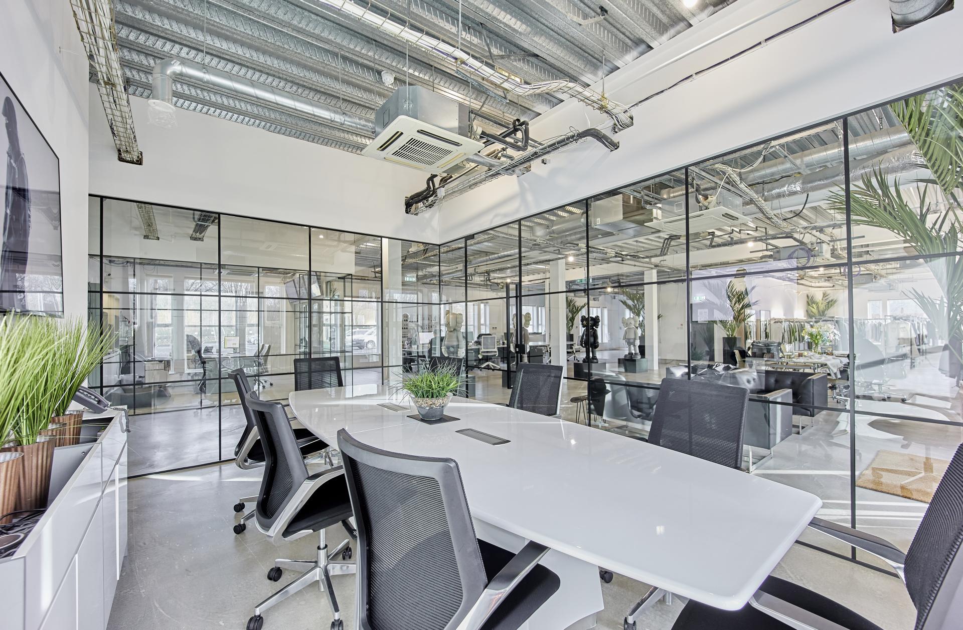 Modern meeting room at MKI HQ featuring glass walls, a sleek table, and greenery for a creative workspace.