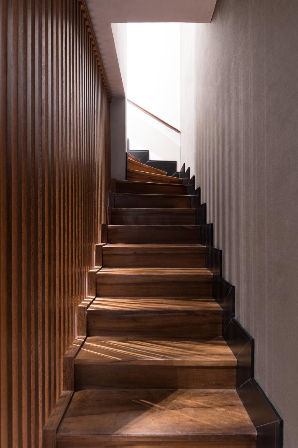 Elegant wooden staircase with natural light filtering in, showcasing the harmonious design of Apto Paulista by Ricardo Abreu Arquitetos.