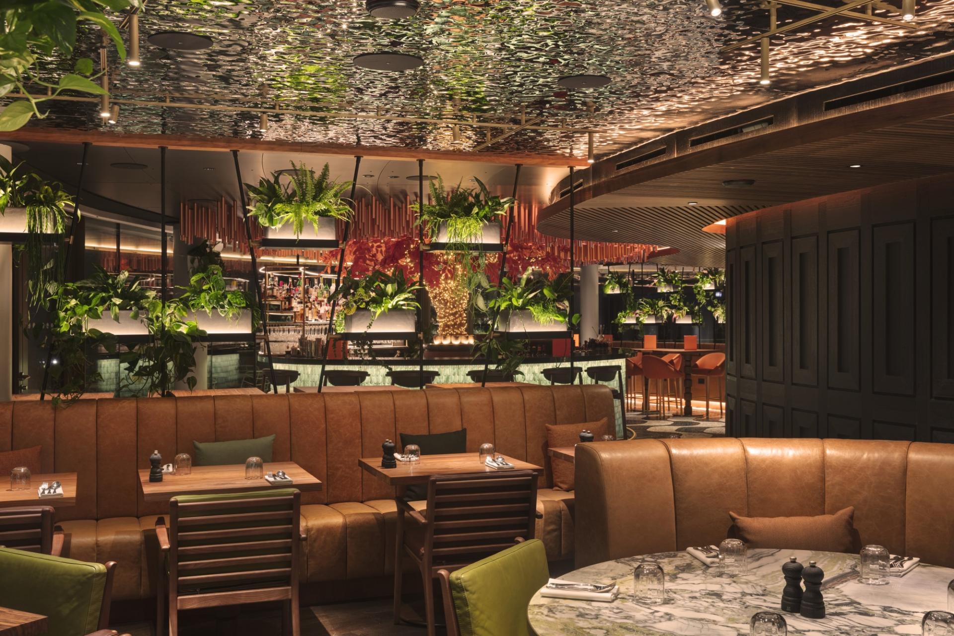 Stylishly designed restaurant interior at W Hotel Edinburgh, featuring lush greenery and modern furniture for a unique dining experience.